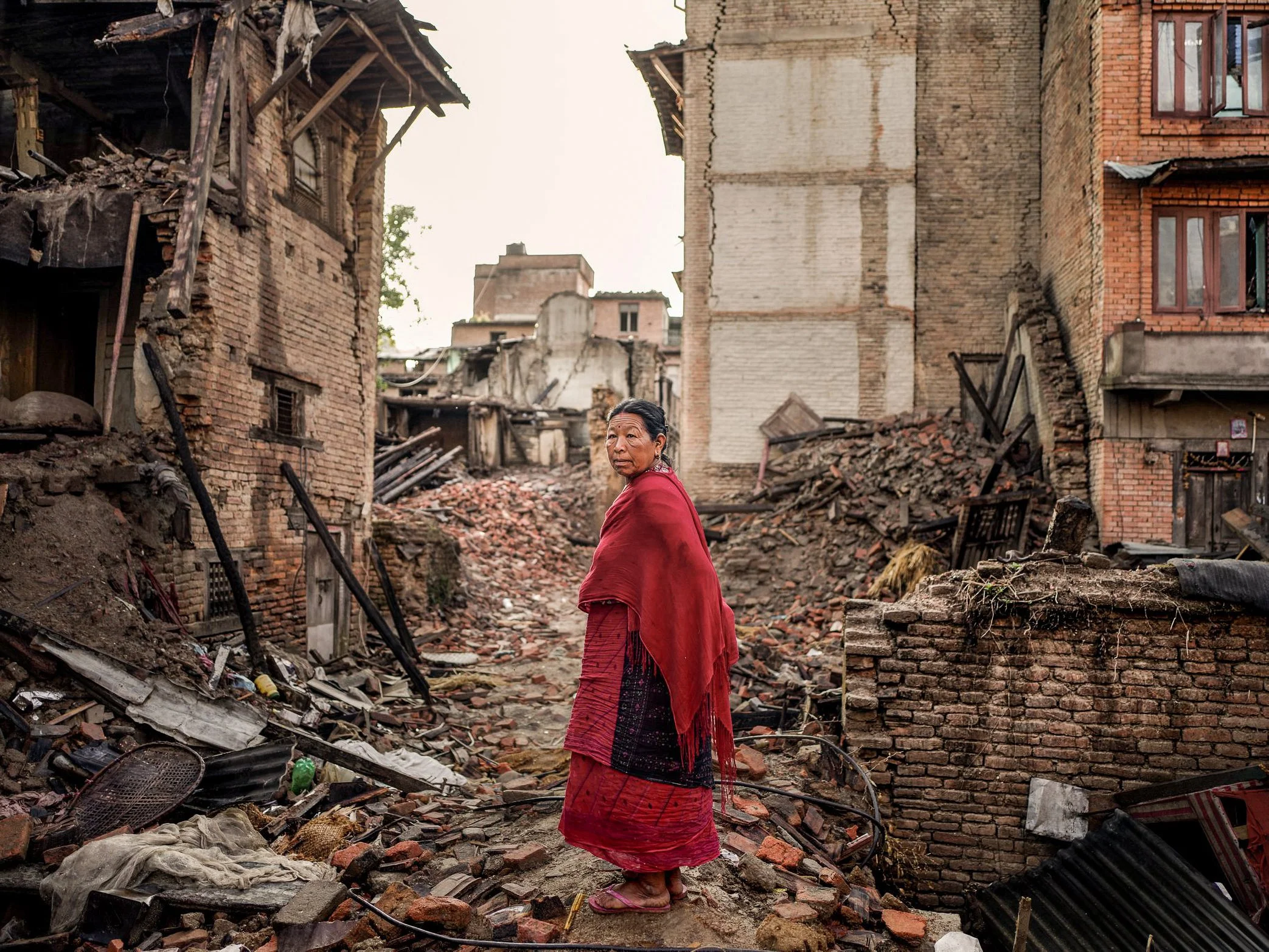 A woman stands among the ruins of Sankhu, a historic town on the edge of the Kathmandu Valley, after the 2015 Nepal earthquake. The magnitude 7.8 quake struck on April 25, killing nearly 9,000 people and damaging or destroying more than 600,000 struc