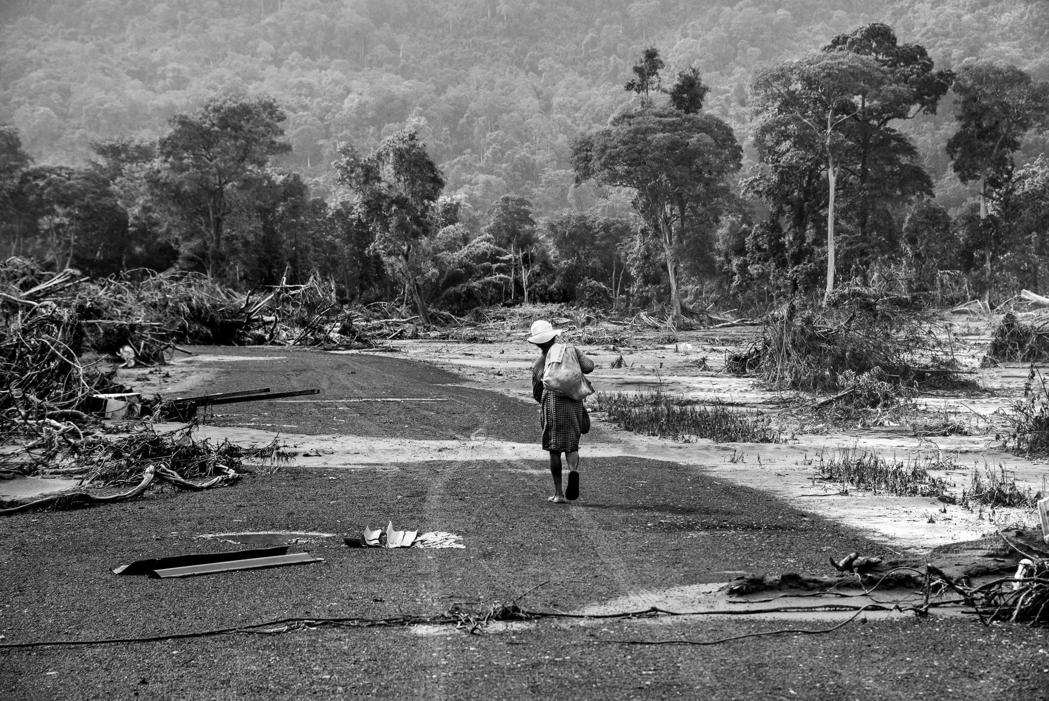 Attapeu, Laos - A villager walks along what was once the main road through her community after the Xe Pian dam collapse. Before the disaster, more than 180 homes stood on both sides of this road; now the village has been reduced to sand, mud, and deb
