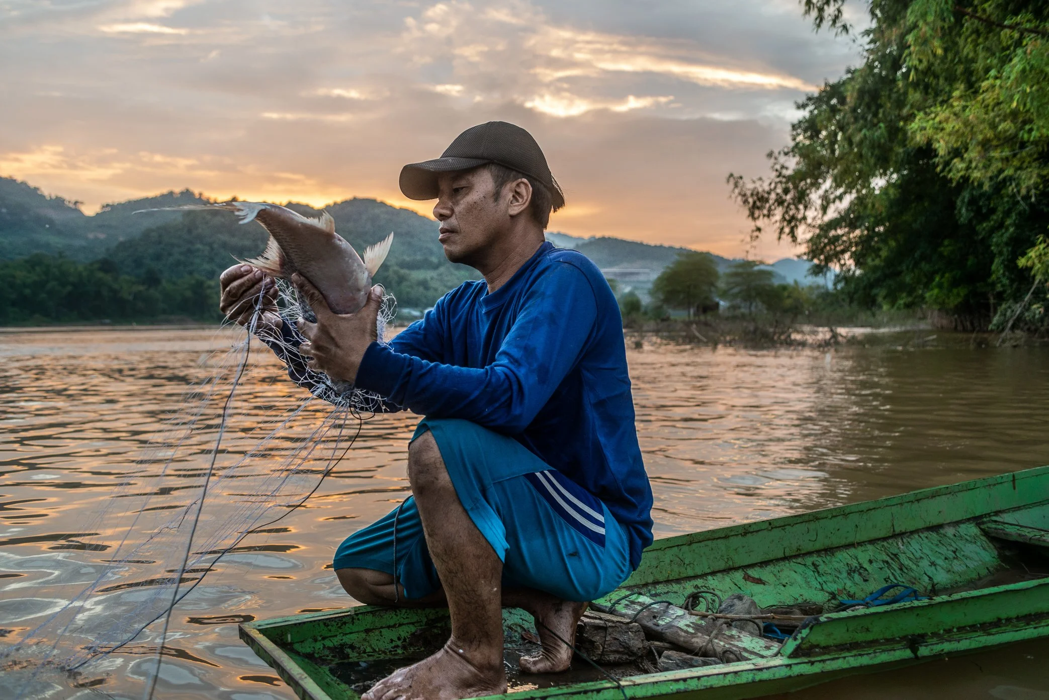 A fisherman from Pak Nam Ou holds his evening catch near the confluence of the Nam Ou and the Mekong. For generations, families here have lived with the river’s natural rise and fall, reading currents, seasons, and fish movements as part of daily sur