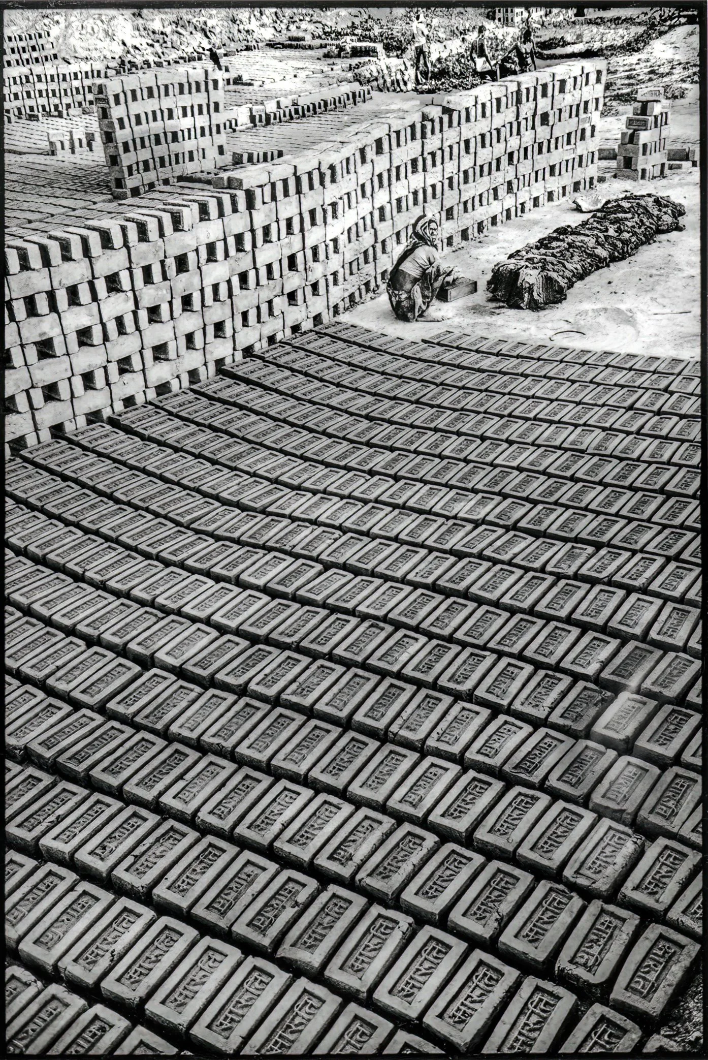 Patna, Bihar, India, April 2003 - A worker shapes wet earth into rows of bricks at a kiln yard in Bihar. Working for long hours in a crouched position, she can produce more than a thousand bricks in a single day.