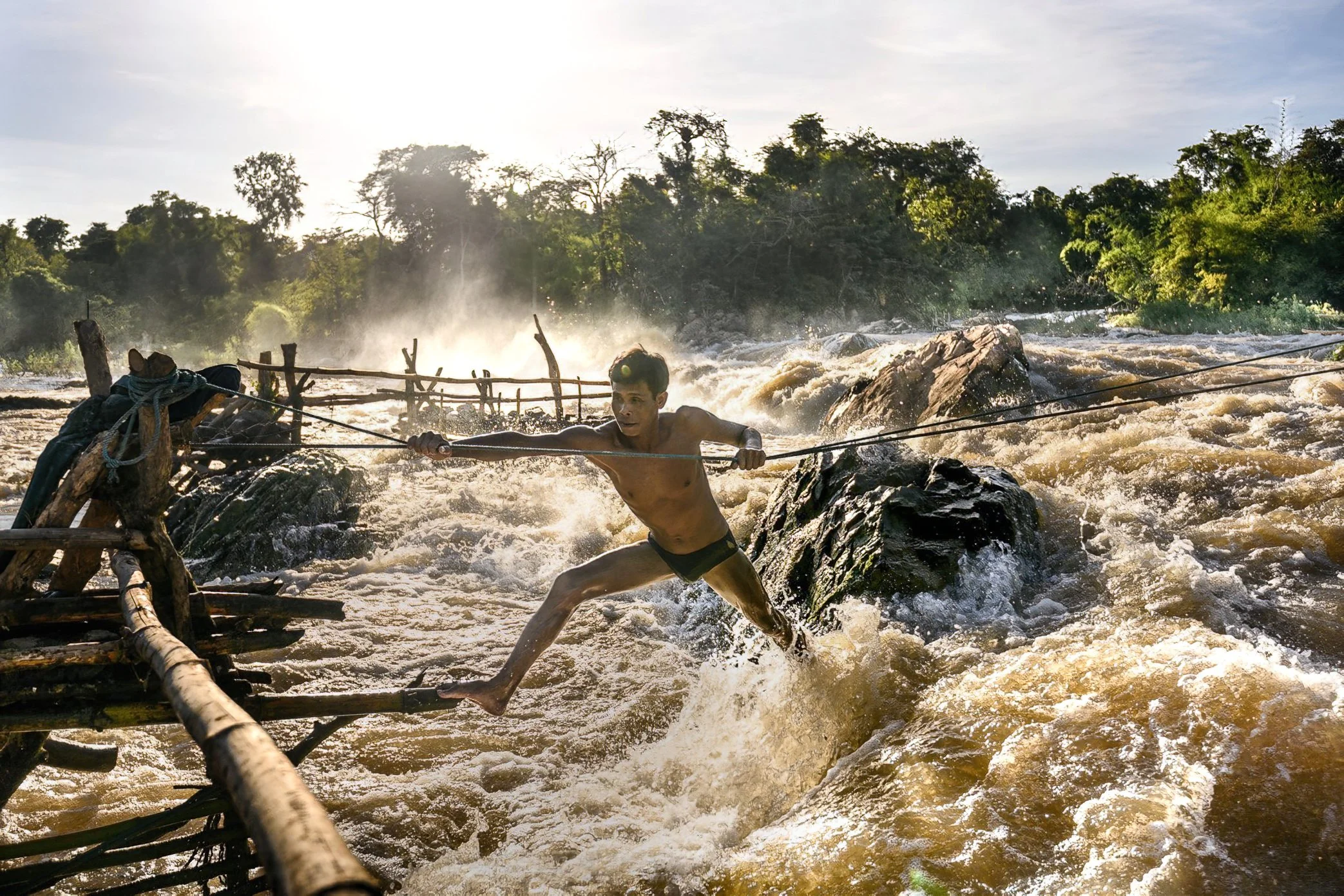 A fisherman moves between Li traps across the rushing water of Khone Falls, using ropes and rock paths known through years of practice. In this landscape, travel itself is part of the work. Each crossing requires balance, timing, and a deep knowledge