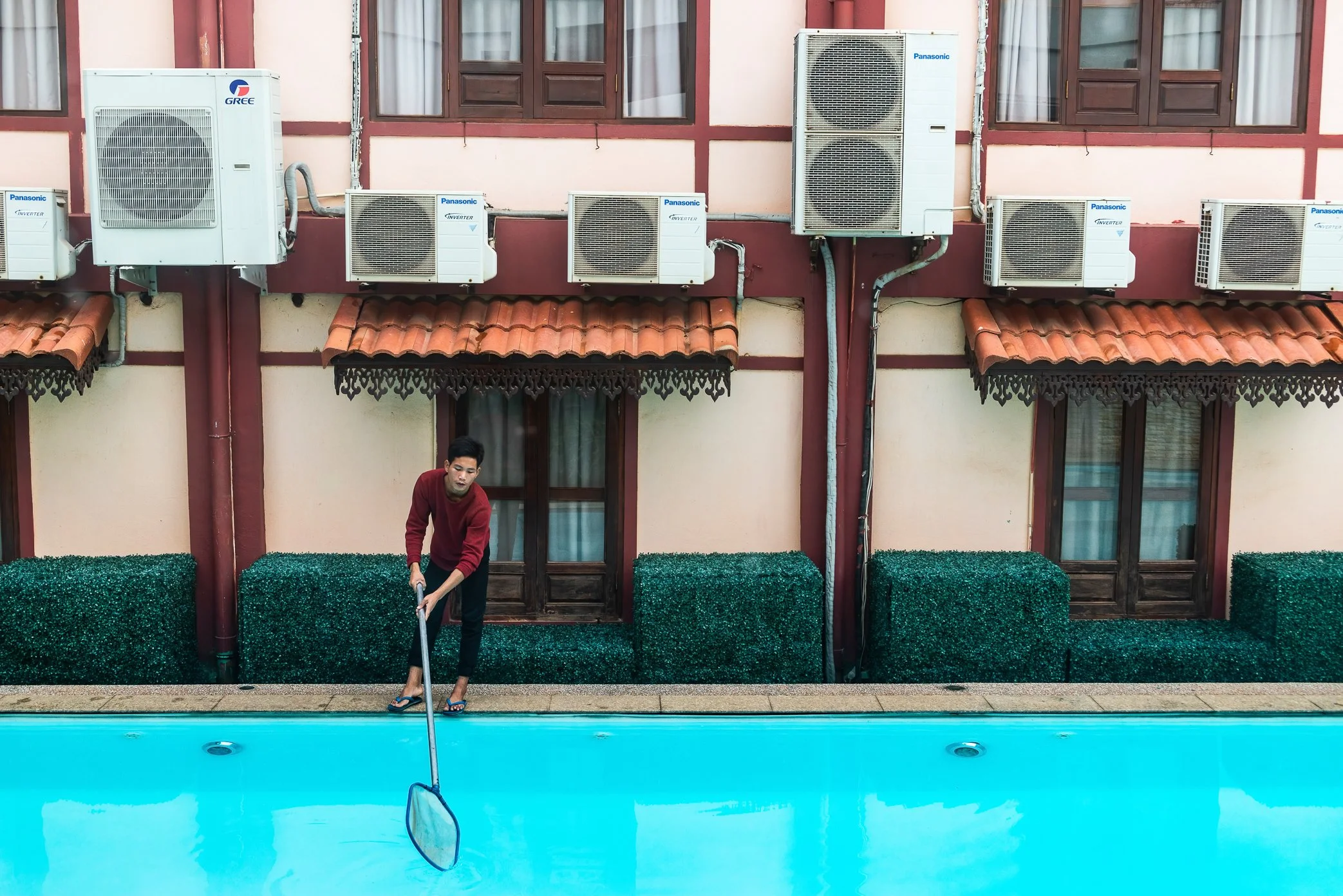 Vientiane, Laos, 2022 - A hotel worker cleans a swimming pool as Laos tries to rebuild its tourism economy after reopening to foreign visitors. But arrivals remain below expectations, and many small hotels, guesthouses, and inns struggle to hire enou