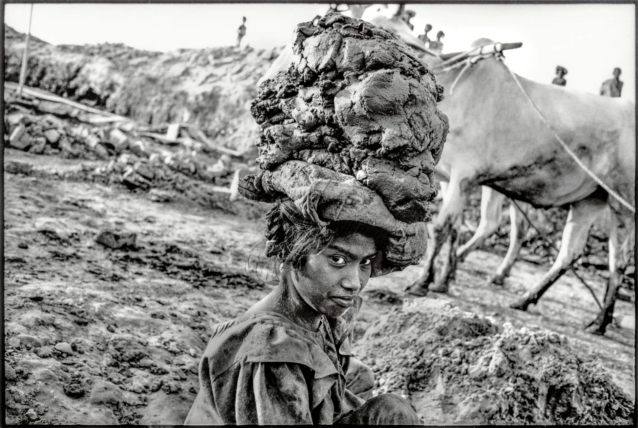 Patna, Bihar, India, April 2003 - A young worker carries wet clay through a brick kiln yard in Bihar. The mud will be shaped by hand into new bricks, part of a family labor cycle that begins before firing and continues until the finished bricks are c