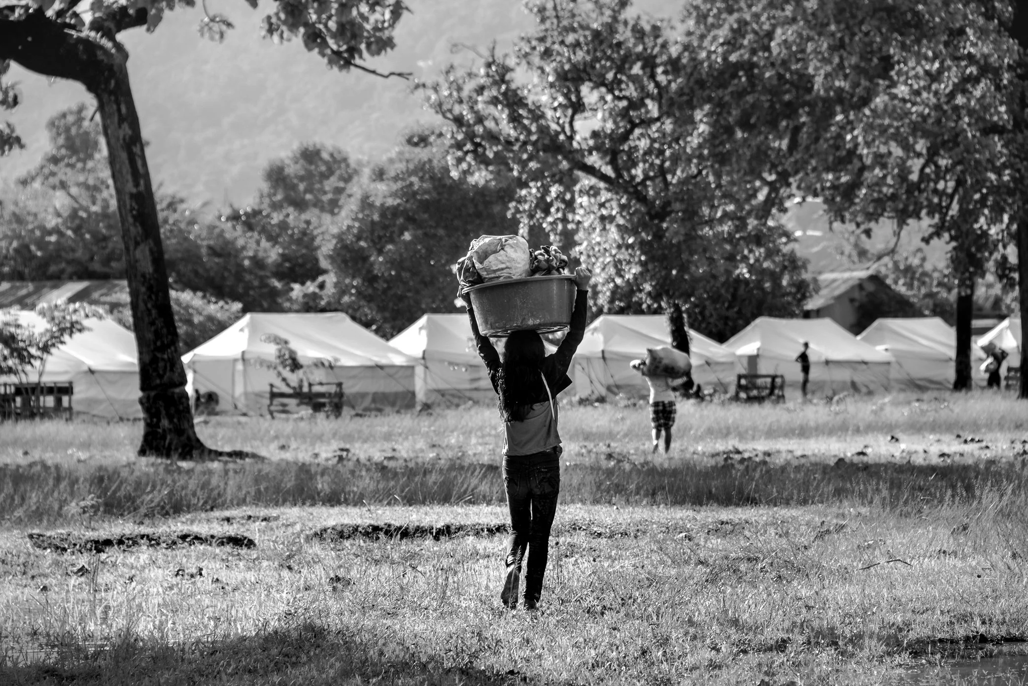 Sanamxai, Attapeu, Laos - A displaced girl carries donated supplies back to her family at the Sanamxai shelter after the Xe Pian dam collapse. Survivors had recently moved from overcrowded school buildings into newly supplied tents, carrying food, cl