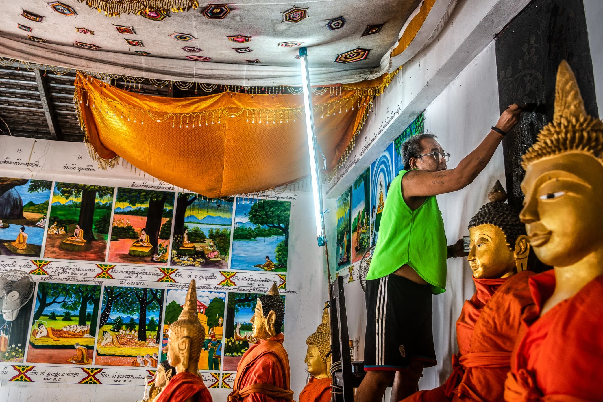 A painter restores murals inside a newly built temple relocated after the Nam Ou dam project changed the original village landscape.

As part of the compensation process, the dam project provided a new temple building, land, and basic utilities. But 