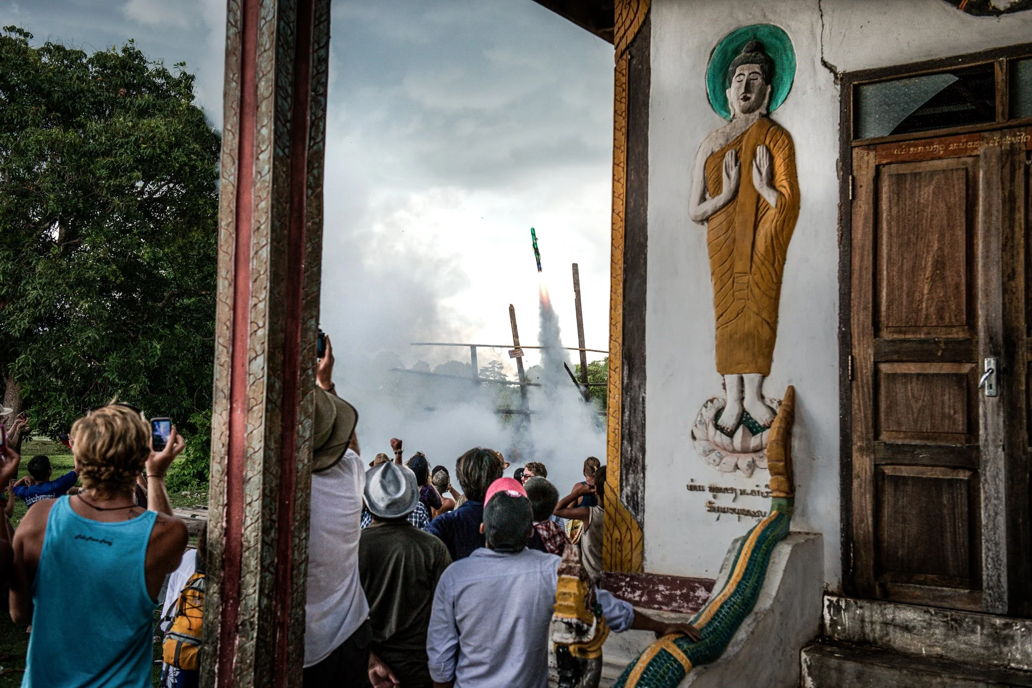 At a temple on Don Det, villagers watch as a homemade rocket rises through smoke during Boun Bang Fai, the Lao rocket festival. Traditionally held before the rains, the festival is both celebration and signal - a call for water, fertility, and renewa