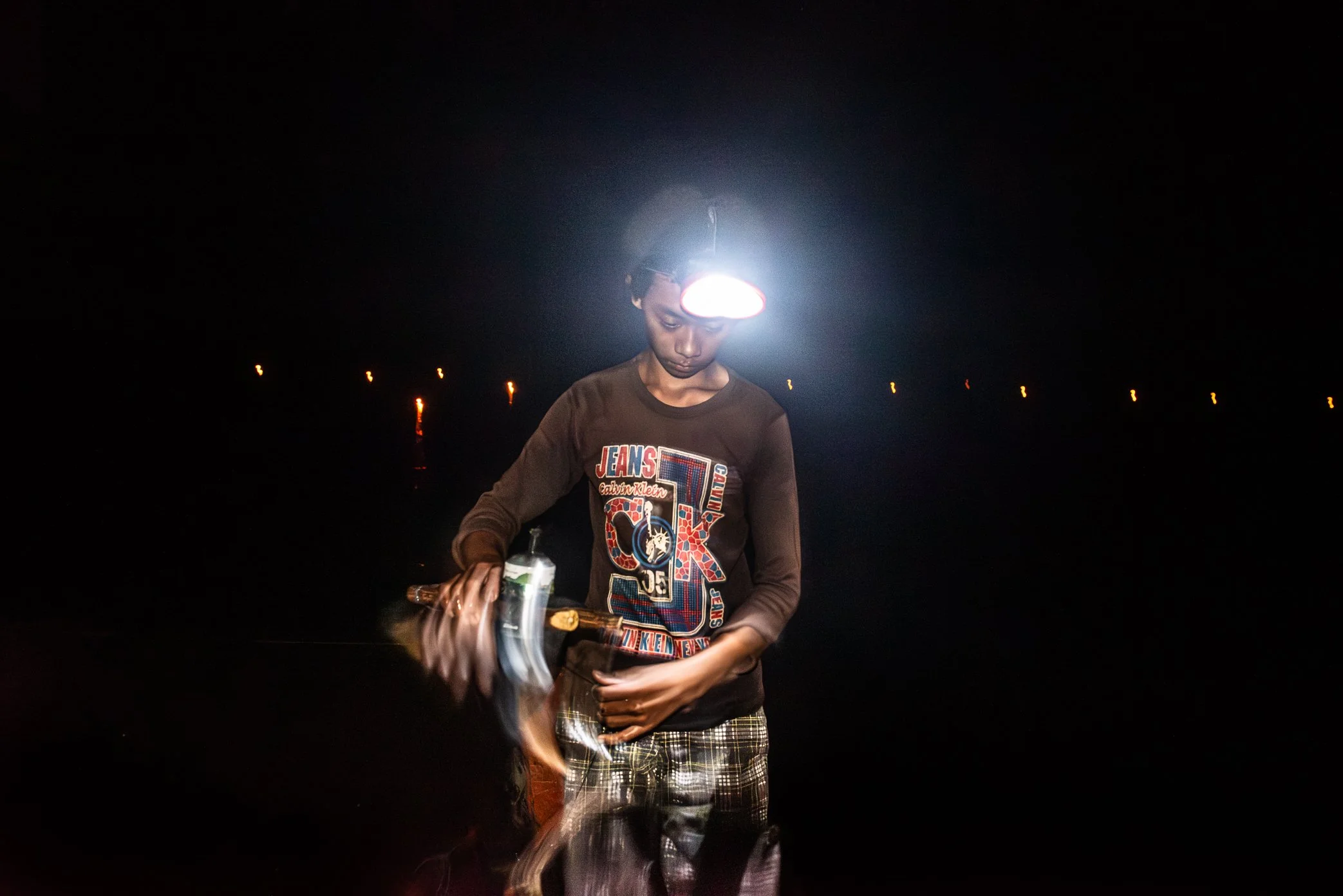 Tonle Sap, Cambodia - After the lamp is lifted from the water, it must be handled carefully before the boat moves on to the next light. Across the dark surface of Tonle Sap, these scattered flames mark both a fishing method and a deeper pressure - th