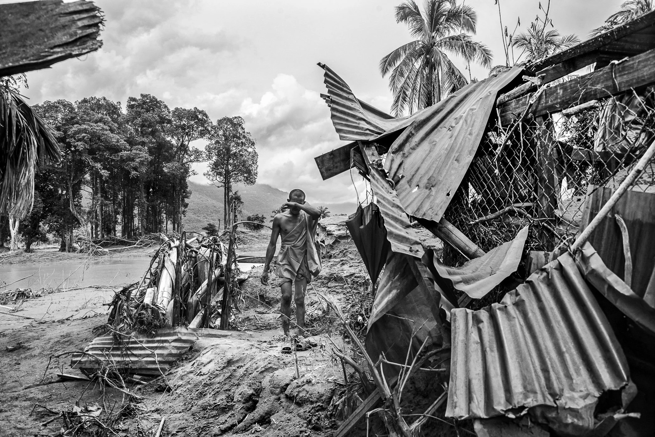 Ban Hinlad, Laos - In the wreckage left behind by the Xe Pian dam disaster, villagers begin returning to search for whatever the floodwaters did not take. Among them is a monk from the village, walking through the remains of shattered homes and twist