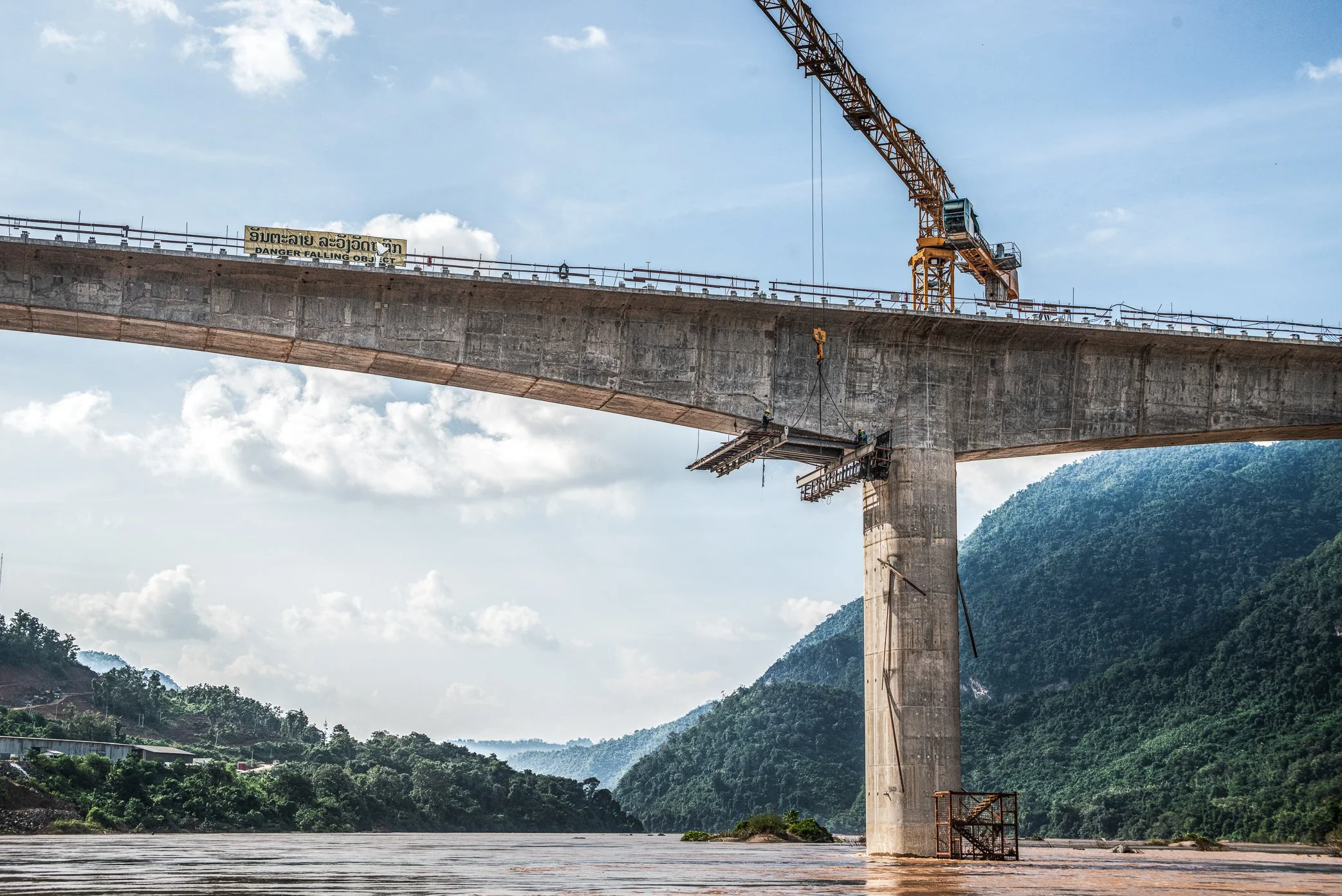 A new bridge rises over the Mekong near the mouth of the Nam Ou, where two rivers meet outside Luang Prabang. Built through a landscape of forested mountains and river villages, the bridge forms part of the expanding infrastructure around the Luang P