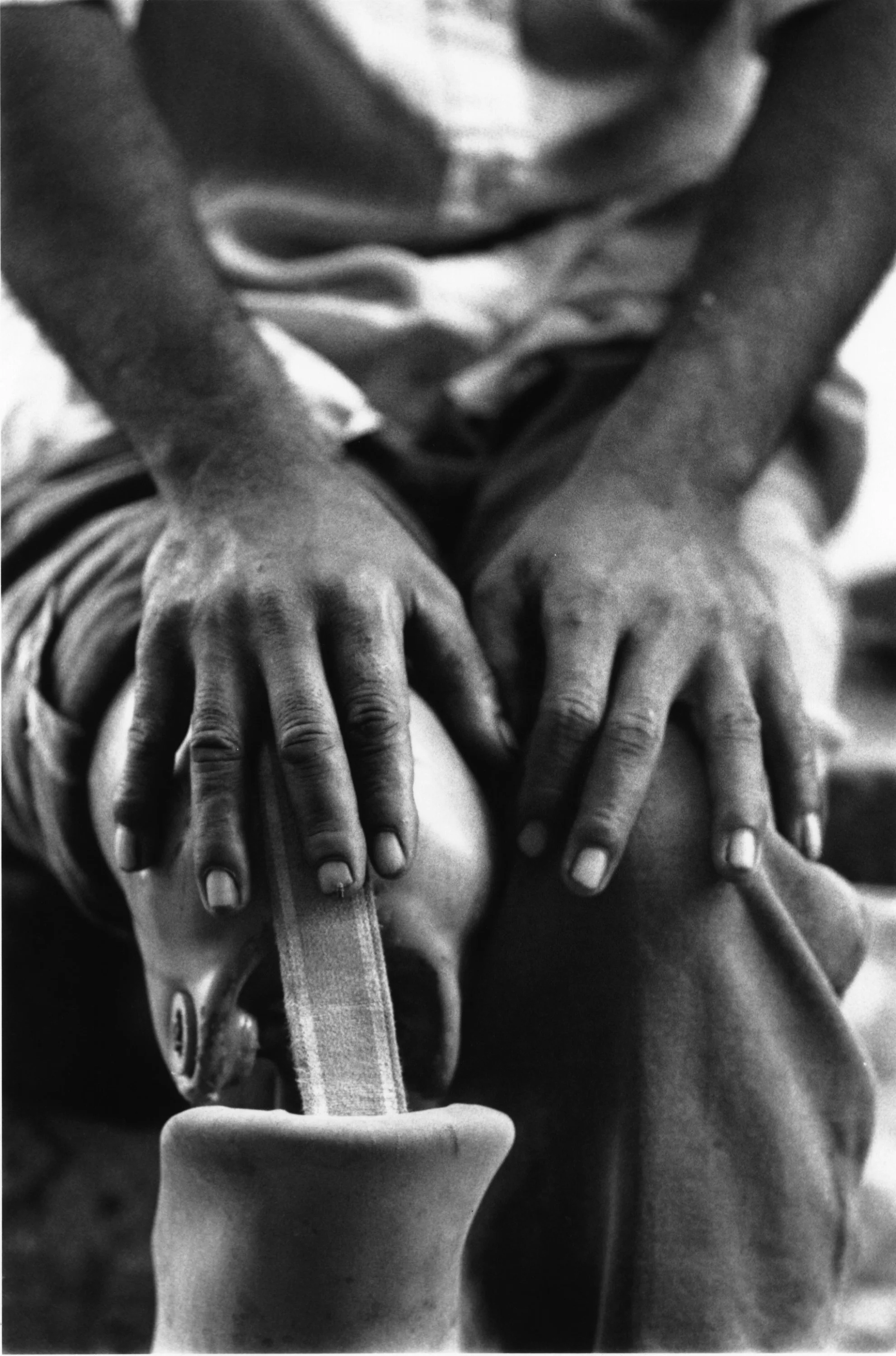 Close-up black and white photo of a child's hands on a medical vent tube.