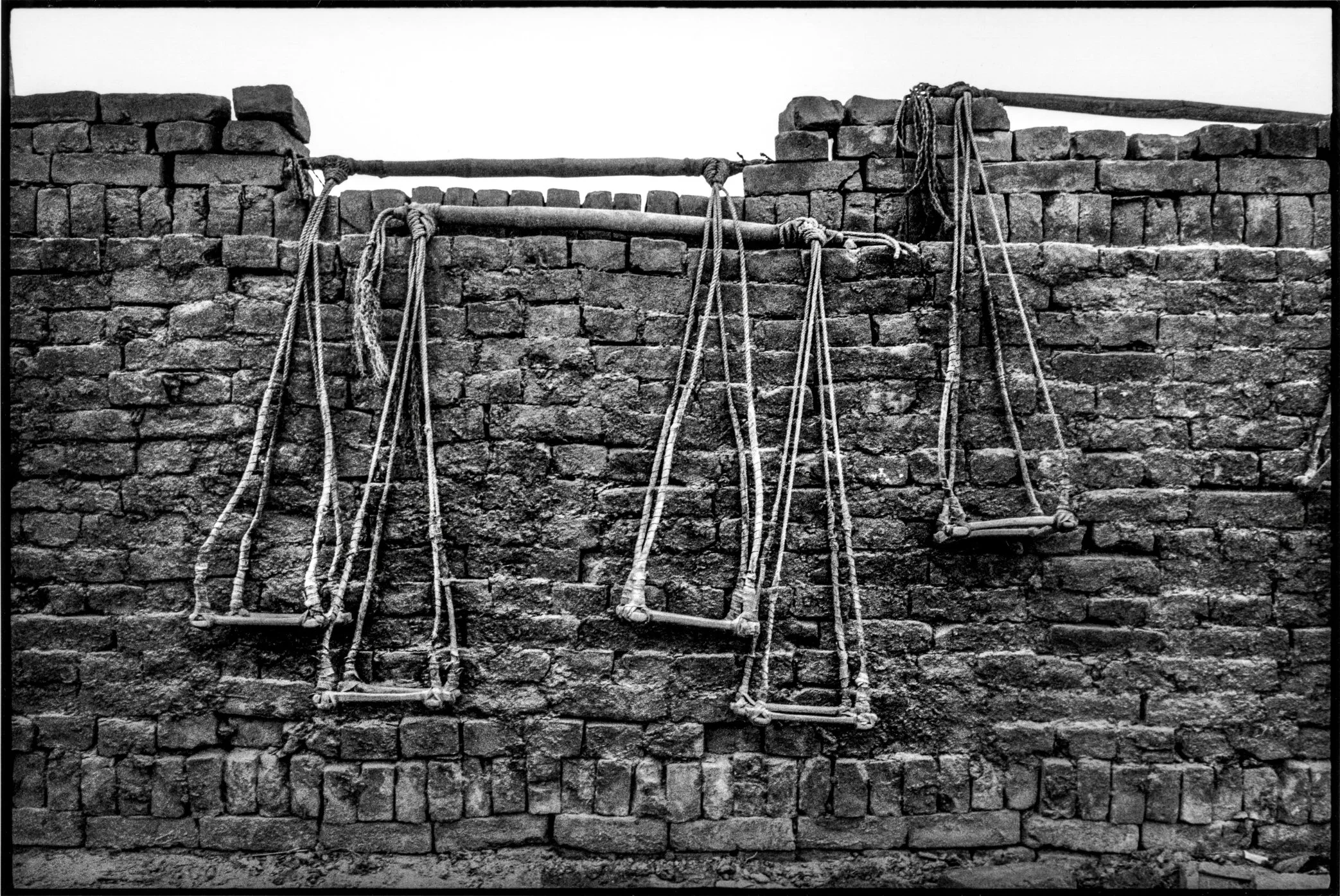 Patna, Bihar, India, April 2003 - After a day of carrying bricks, workers’ baskets hang from the kiln wall. The tools of labor are left in place, waiting to be lifted again with the next day’s work.