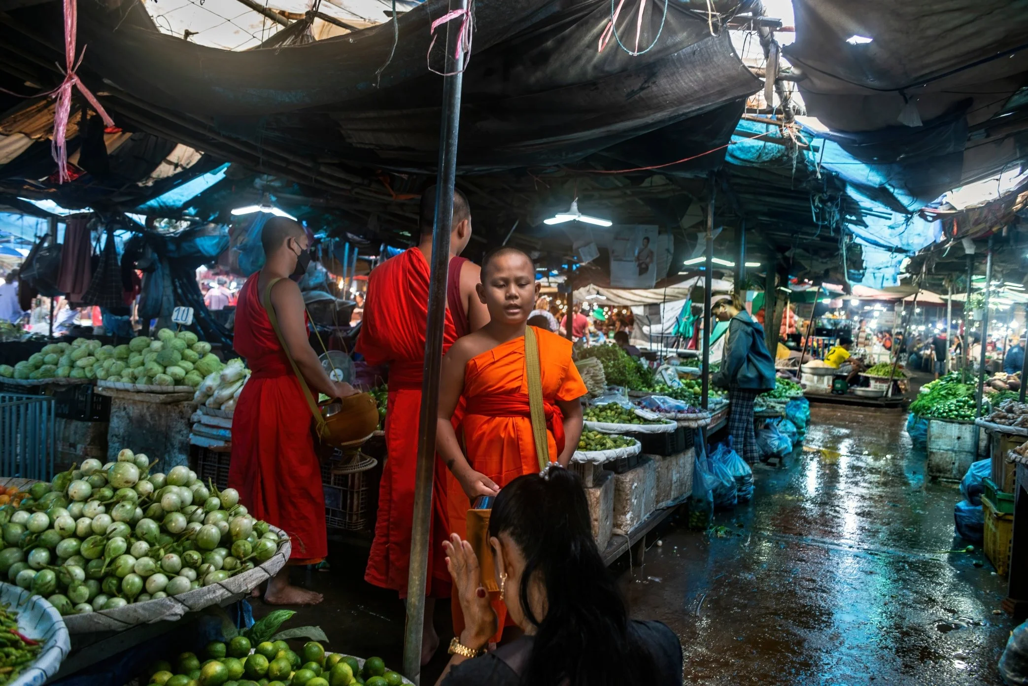 Vientiane, Laos, 2022 - Monks receive morning offerings from vendors at Oxy wholesale fresh market, where faith and commerce meet before the day’s trading begins. As Laos faces rising prices, a weakened kip, and the wider effects of global economic s