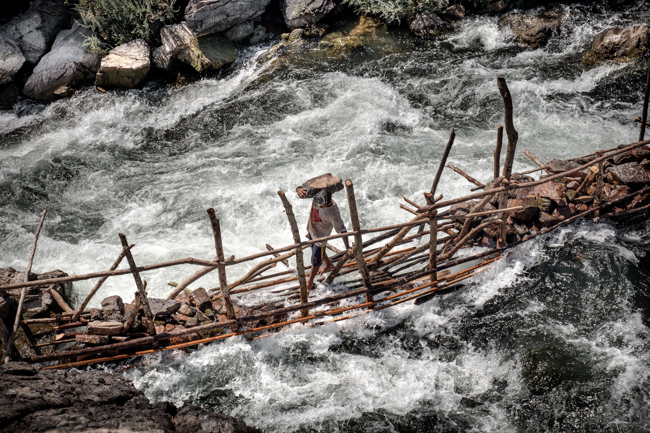 Building the foundation of a Li trap begins with the hardest labor: moving stones into the current to create a base strong enough to withstand the force of the Mekong. At this site in Si Phan Don, set beside a cluster of waterfalls, that work becomes