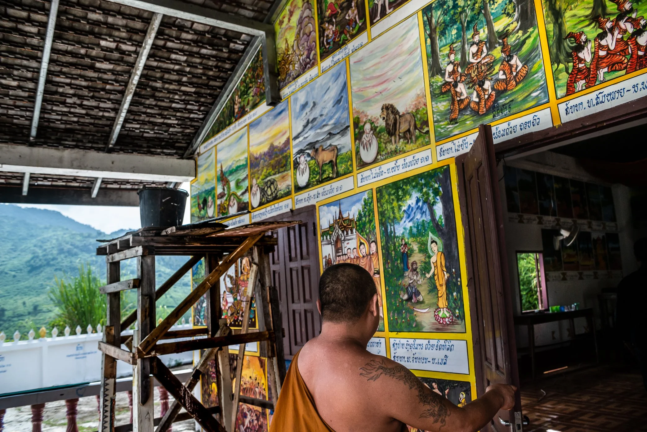 A monk opens the door to the newly painted ordination hall of a relocated village temple along the Nam Ou River.

After the dam project provided only the basic temple structure, villagers raised their own money to restore what made the temple feel co