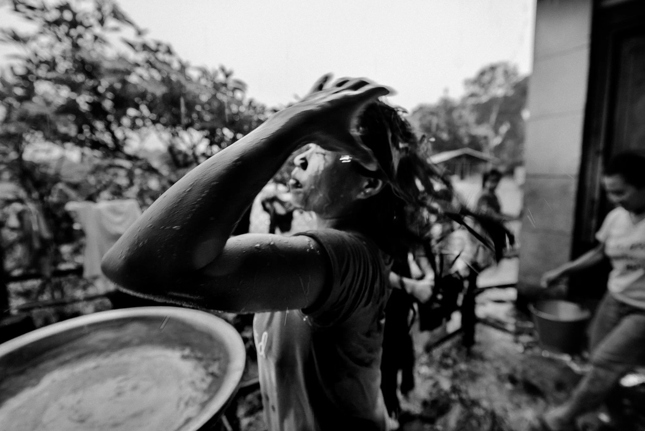 Tamoyot Shelter, Attapeu, Laos - A displaced girl from Hin Lat washes her hair at the Tamoyot shelter after the Xe Pian dam collapse. Far from the village she once knew, daily routines continue in temporary spaces - bathing, eating, waiting, and tryi