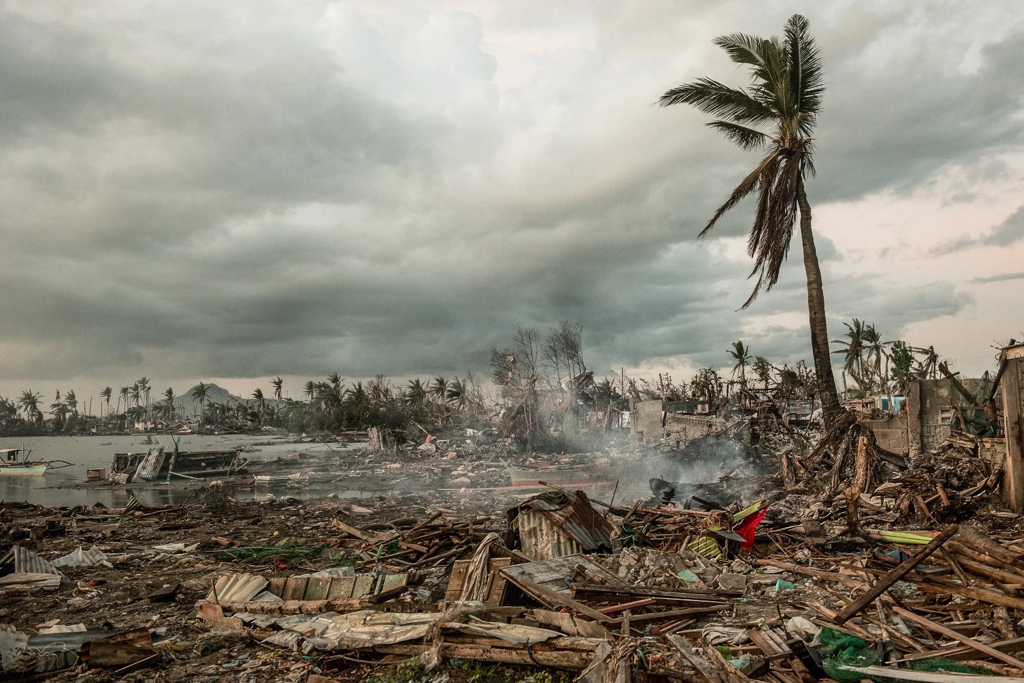 Barangay Alimasay, Leyte, Philippines, 2013 - In the “crab zone” of Barangay Alimasay, storm surge from Typhoon Haiyan swept through a coastal community of about 600 people. Nearly half the village was lost. Weeks later, smoke rose from the wreckage,