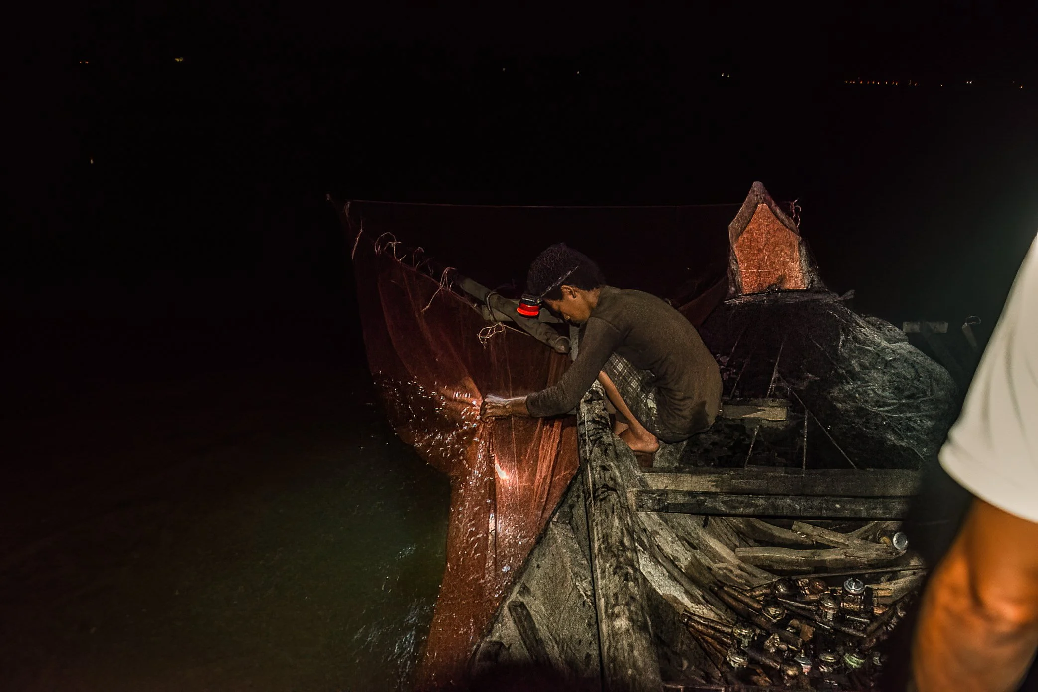 Tonle Sap, Cambodia - All night, the work repeats: lift the lamp, gather the fish, reset the net, move toward the next flame. On Tonle Sap, oil-lamp fishing is illegal, but it is also part of a harsher reality - a lake under pressure, fish stocks in 