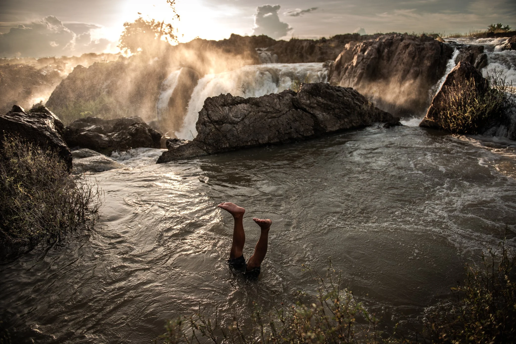 Fishermen in Si Phan Don often turn the river into both workplace and proving ground. In the calmer pockets beside the falls, displays of underwater agility can seem playful, but such skills have practical value in a landscape shaped by violent curre