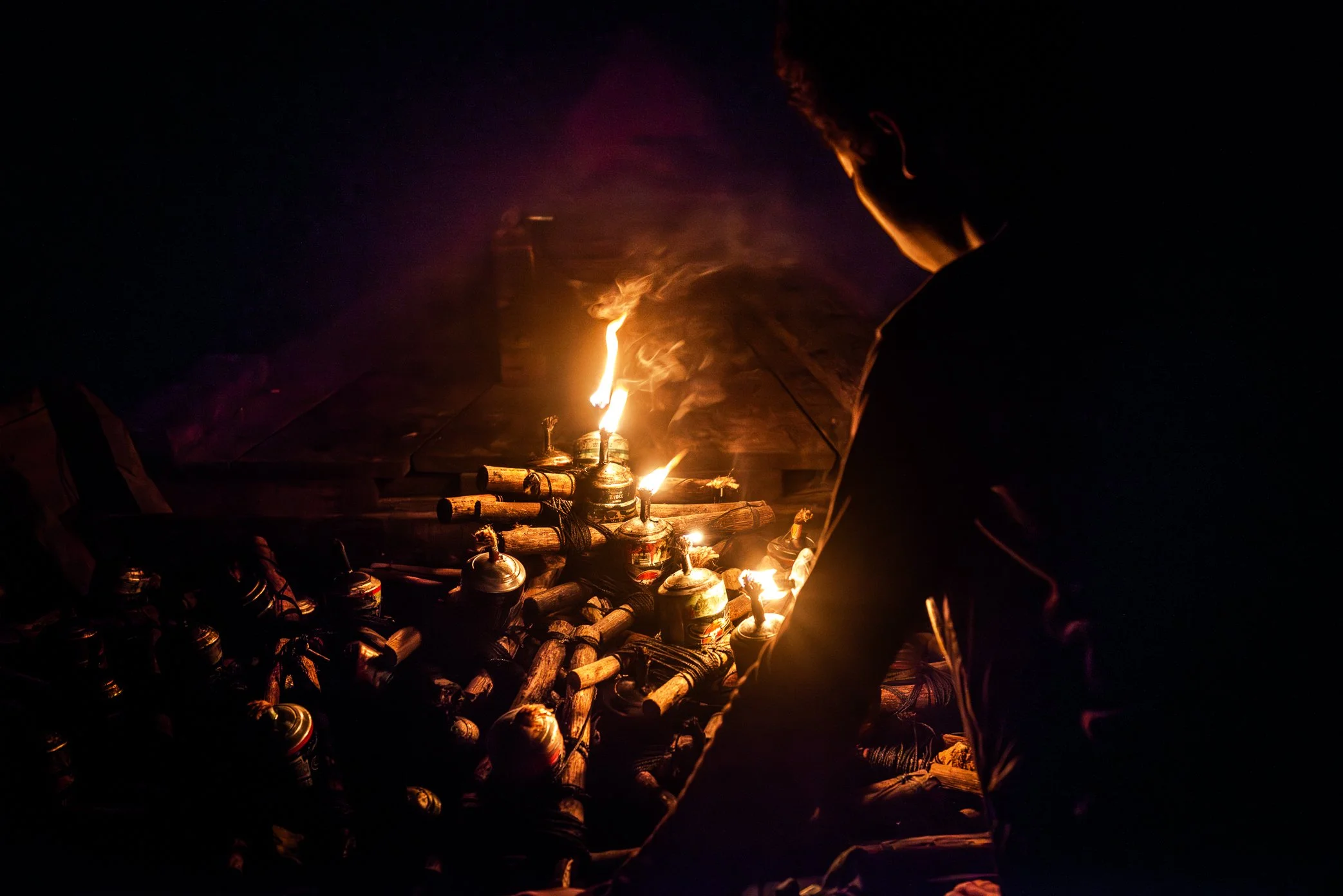 Tonle Sap, Cambodia - A fisherman prepares kerosene lamps before setting them across the dark water of the Tonle Sap. Each flame is used to draw insects, and with them, fish rising from below. On nights like this, the boat becomes both workplace and 