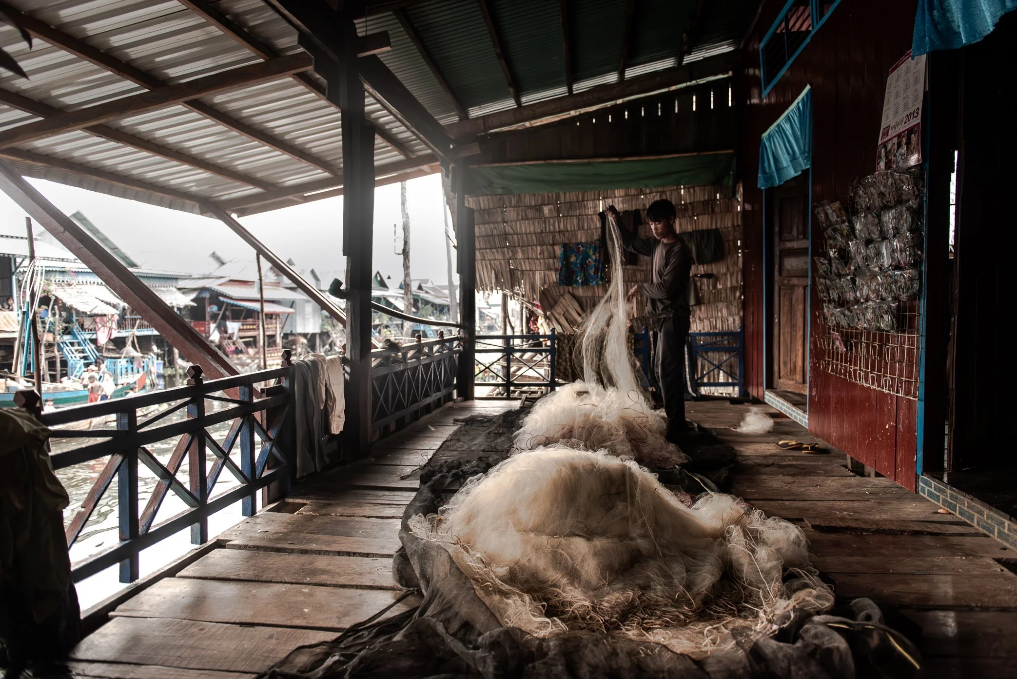 A fisherman cleans and repairs a fishing net outside his home in Kampong Phluk, Cambodia. The net stretches nearly 2,700 meters, a scale that reflects both the dependence of local families on the Tonle Sap fishery and the growing pressure on the lake