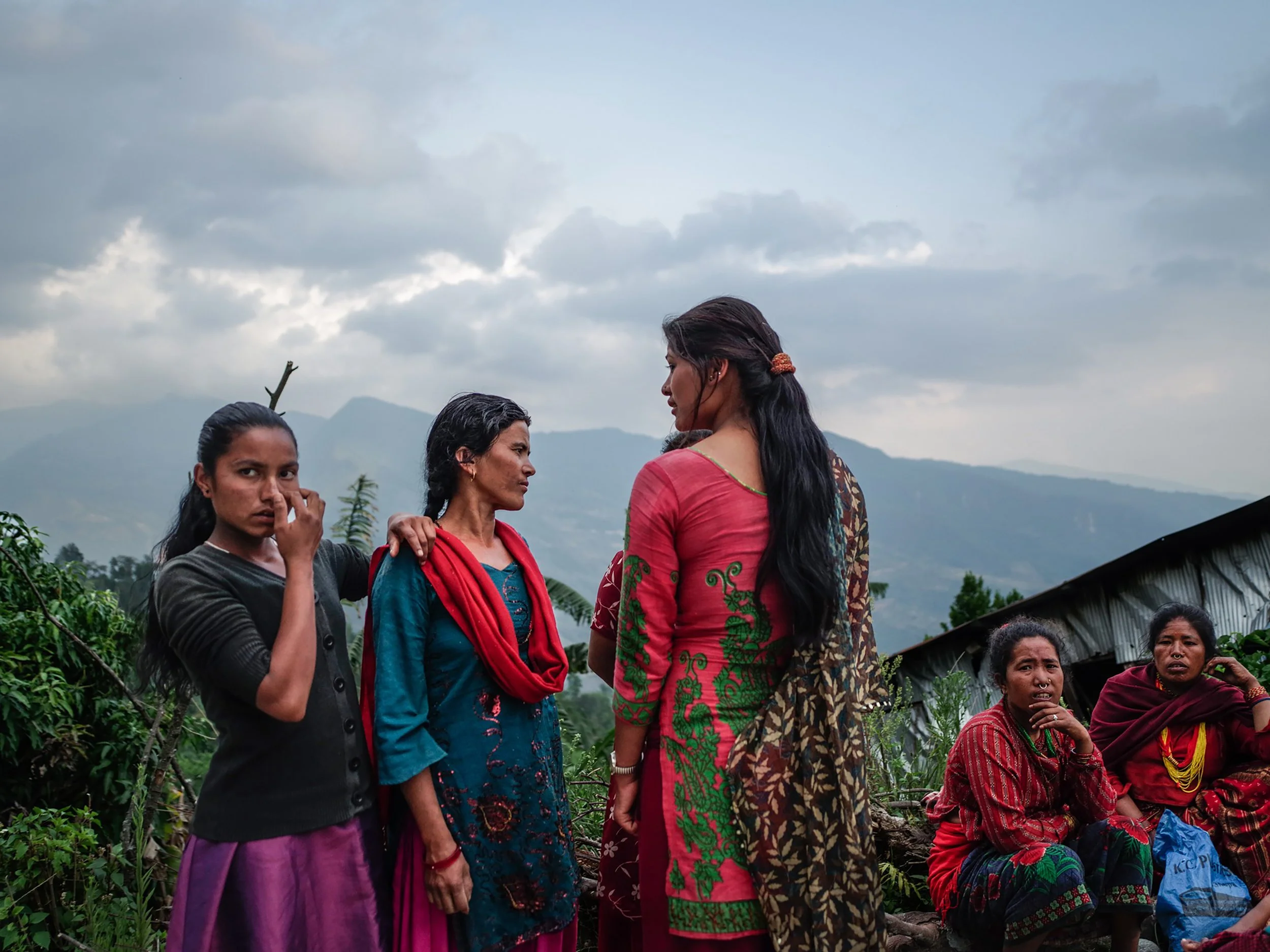 Women wait along a roadside for relief supplies after the 2015 Nepal earthquake. In the hardest-hit districts outside Kathmandu, families gathered wherever aid trucks stopped, hoping food, tarpaulins, blankets, or basic household items would last unt