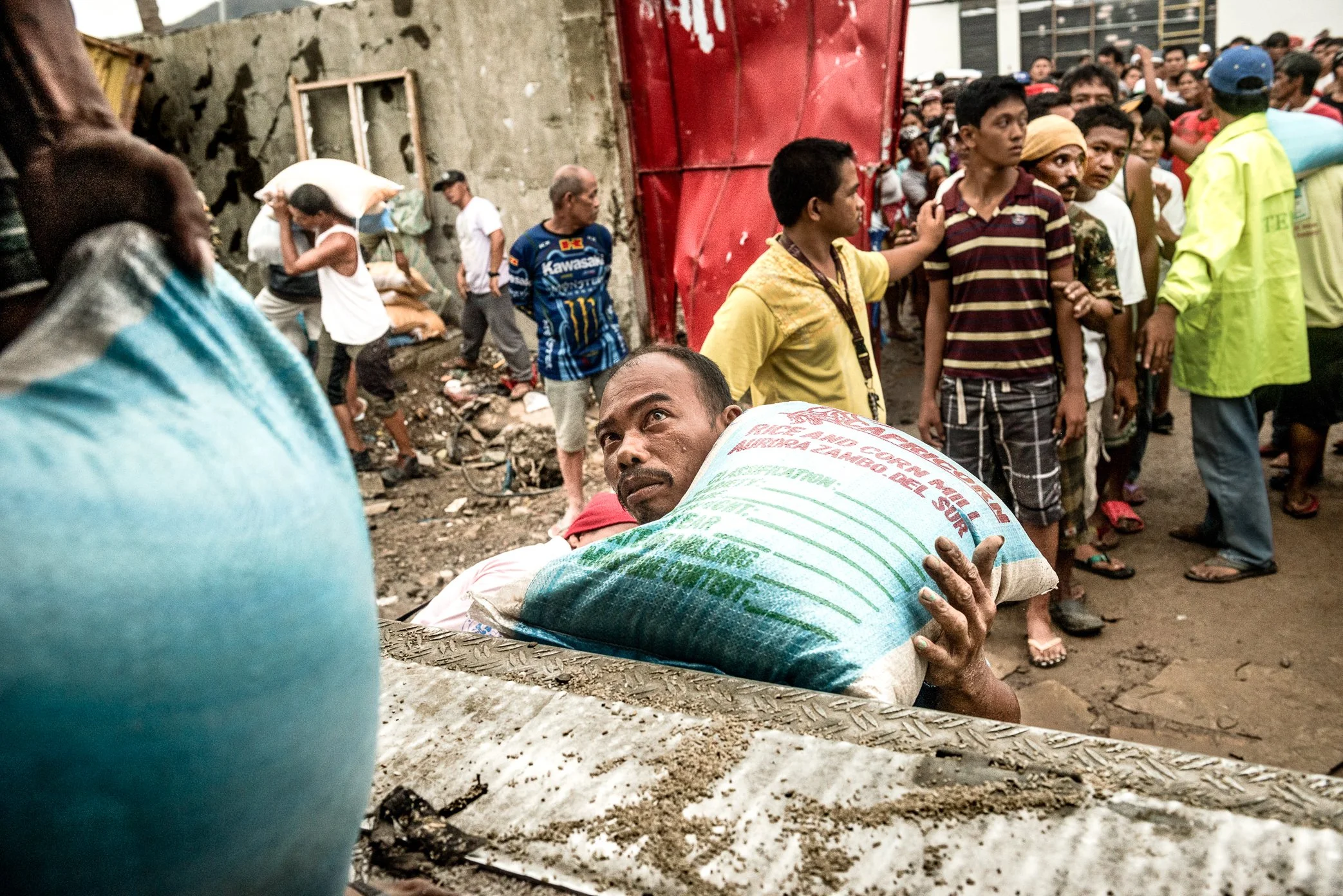 Tacloban, Philippines, 2013 - Police secure a truck carrying food aid as hundreds of survivors wait in line for relief supplies after Typhoon Haiyan. For many families, standing for hours became part of daily survival, with no guarantee that food wou