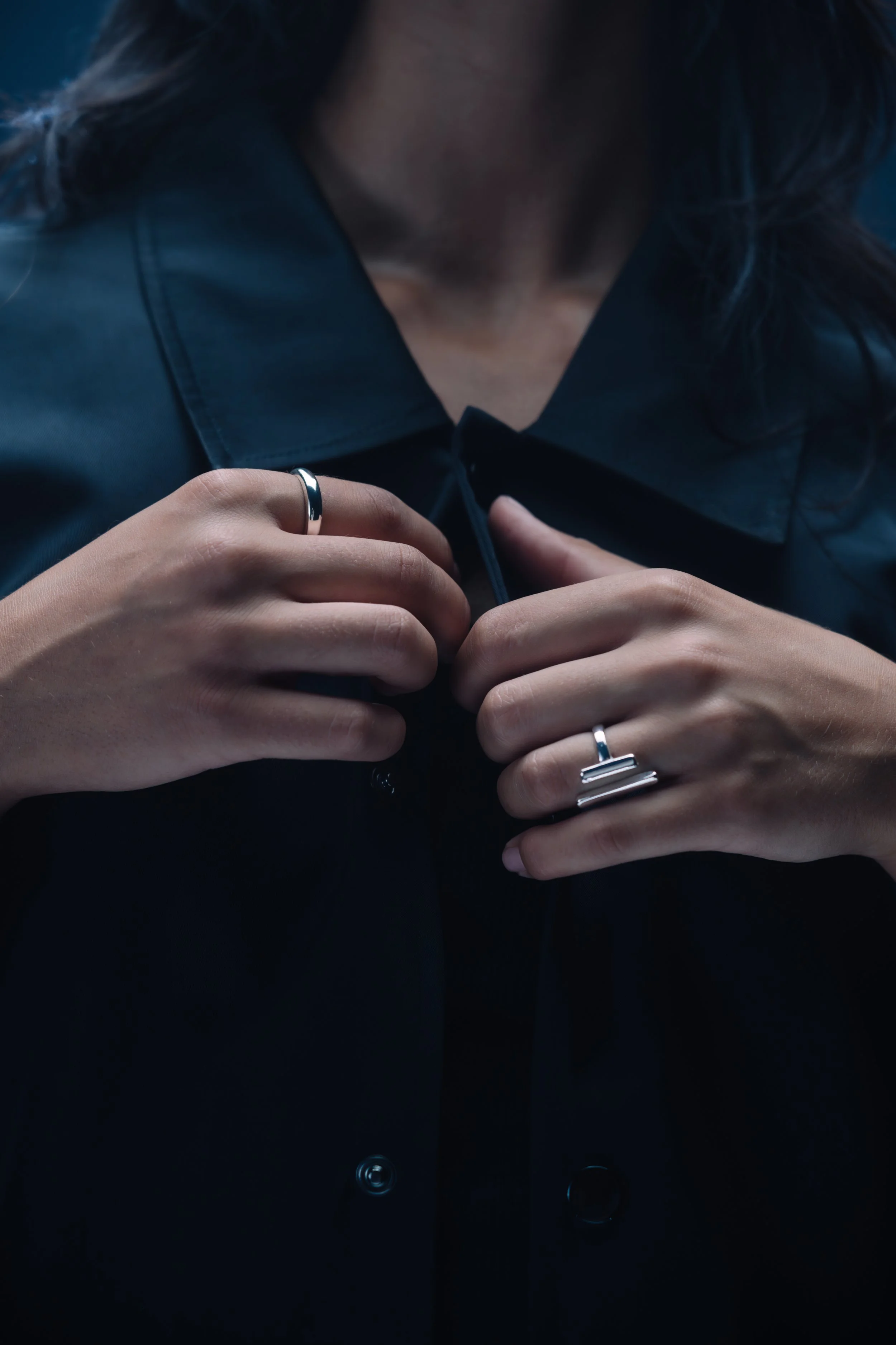 Nahaufnahme von einer Person in schwarzer Jacke, die einen Reißverschluss schließt. Die Person trägt zwei silberne Ringe an den Fingern.