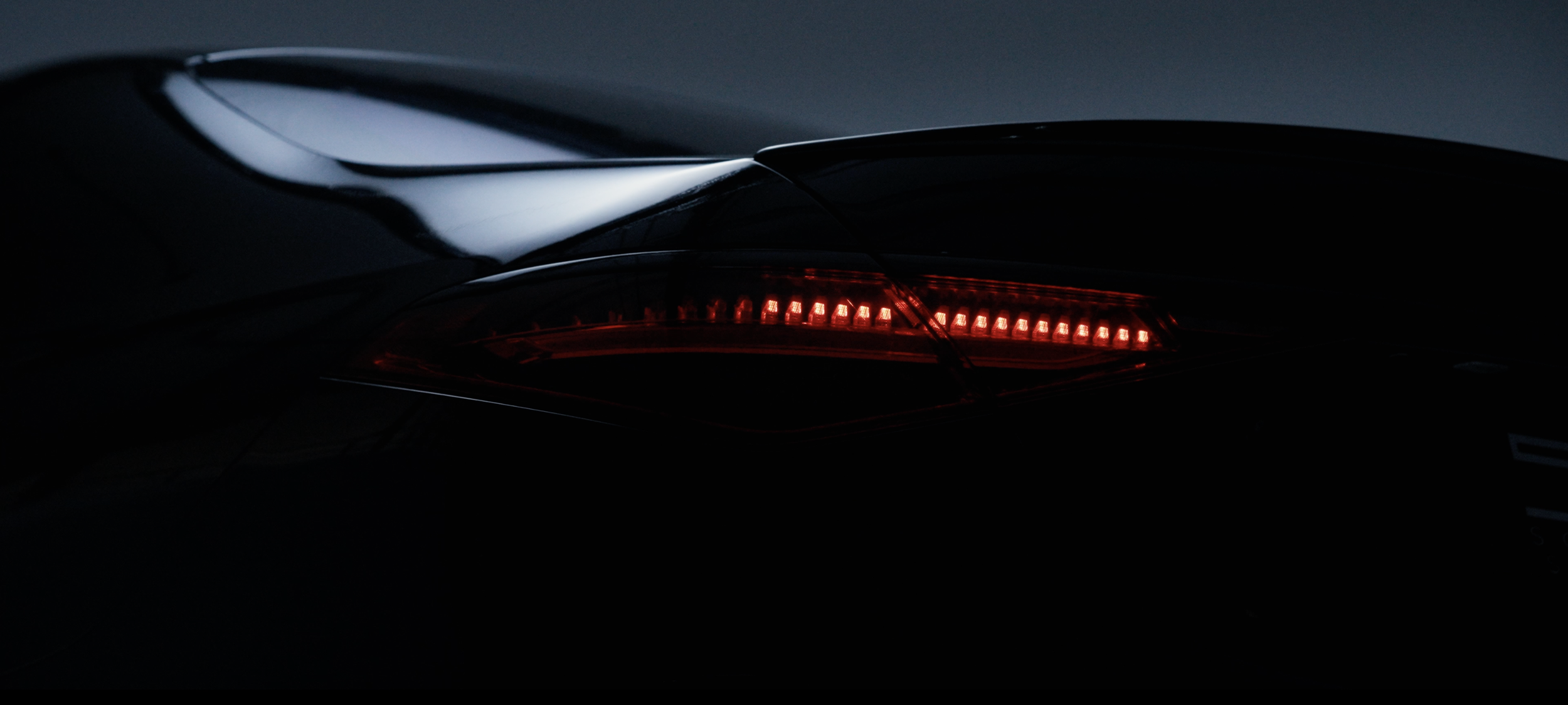 Nahaufnahme des Rücklichts eines schwarzen Autos bei Nacht.