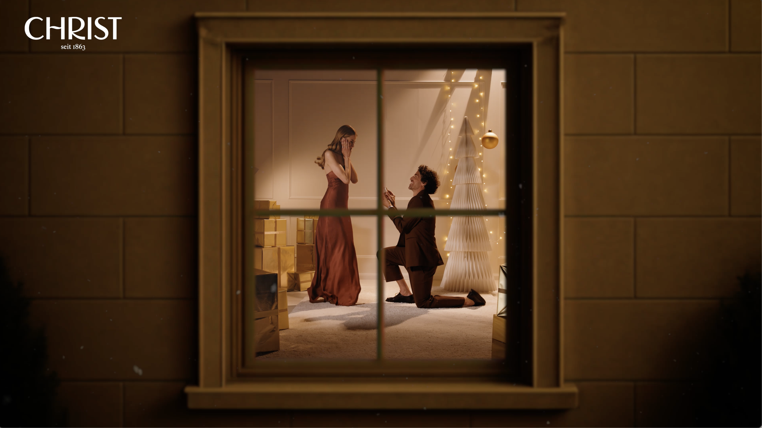 Ein Mann macht einem überraschten, tränenreichen Mädchen einen Heiratsantrag in einem festlich geschmückten Raum, sichtbar durch ein Fenster von außen aufgenommen.