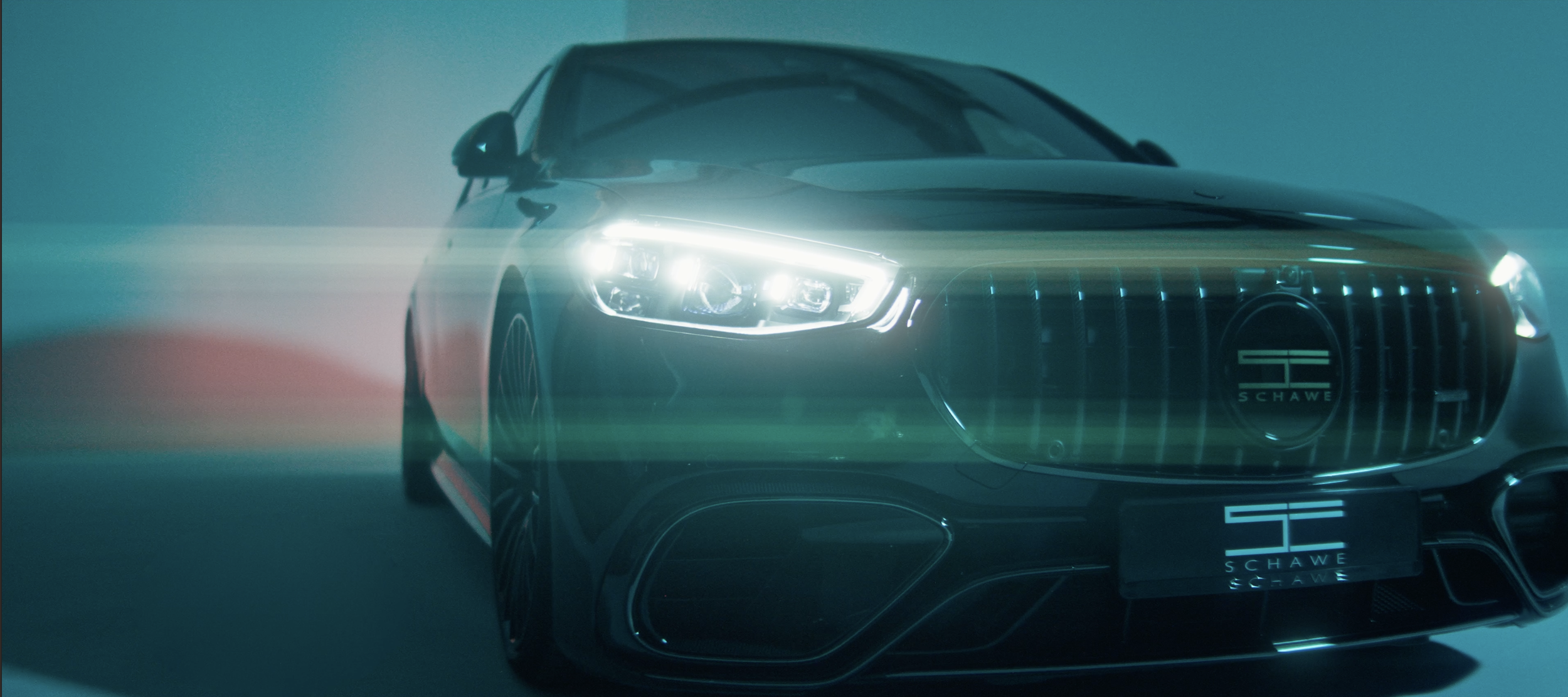 Ein schwarzer Luxuswagen mit LED-Scheinwerfern, aufgenommen in einem hell erleuchteten Raum mit bläulichem Licht, zeigt die Front und die linke Seite des Autos.