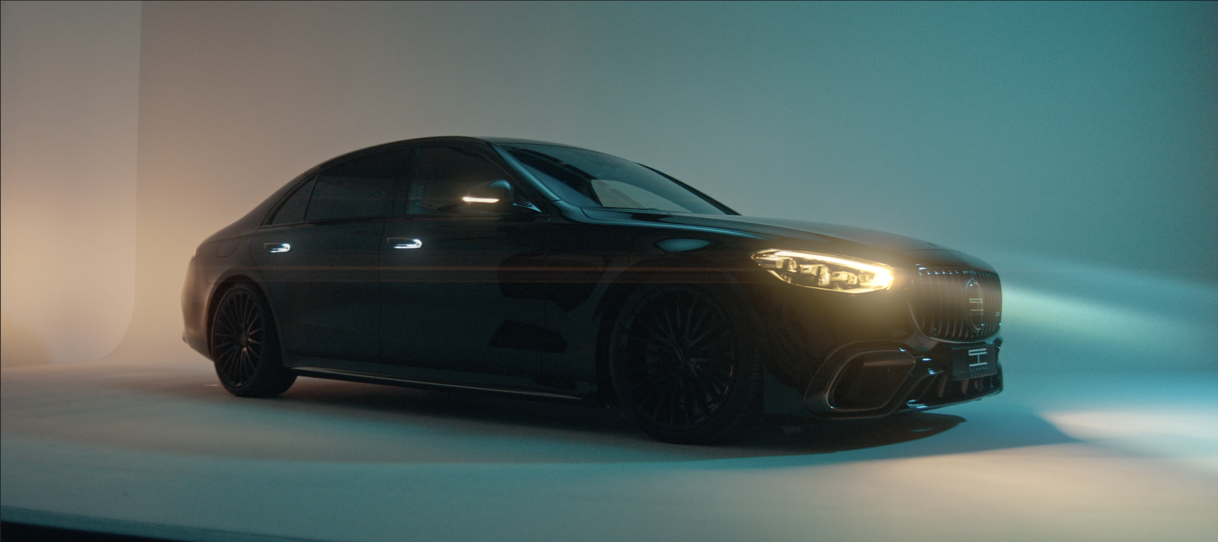 Ein schwarzes Luxusauto mit leuchtenden Scheinwerfern in einem minimalistischen Raum mit weichem Licht.