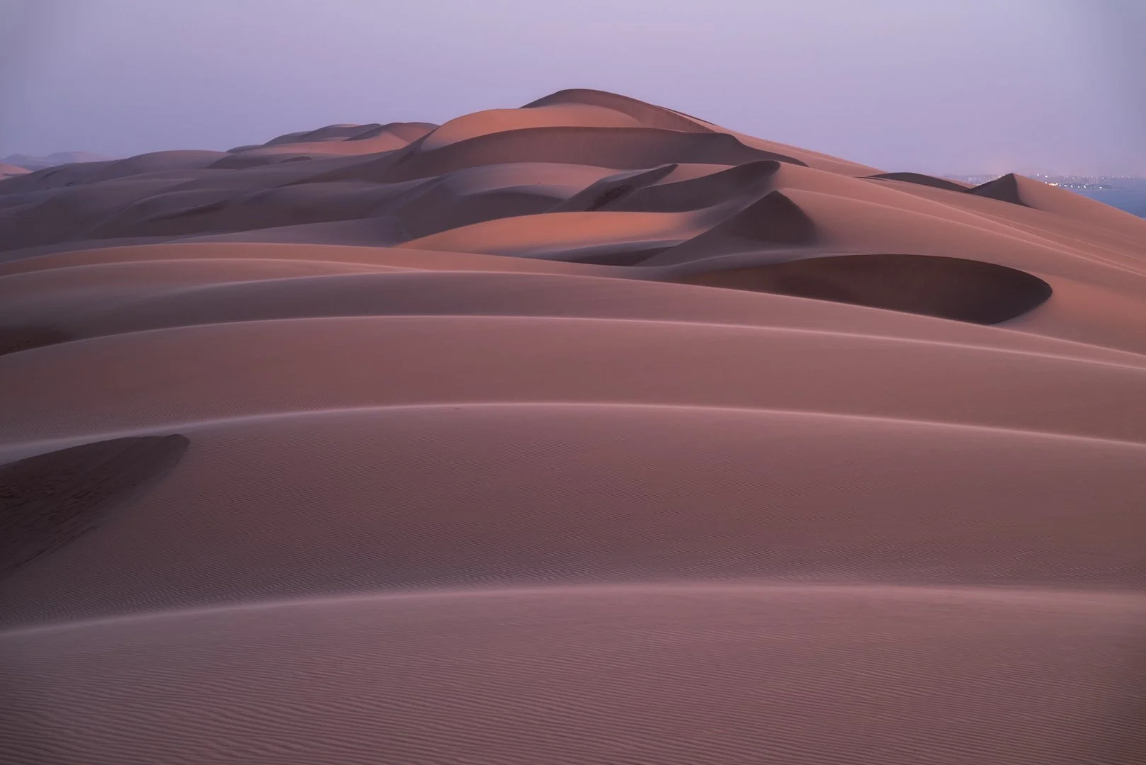 Namibian Dunes near Swakopmund after sunset with pink and purple hues in the sky.