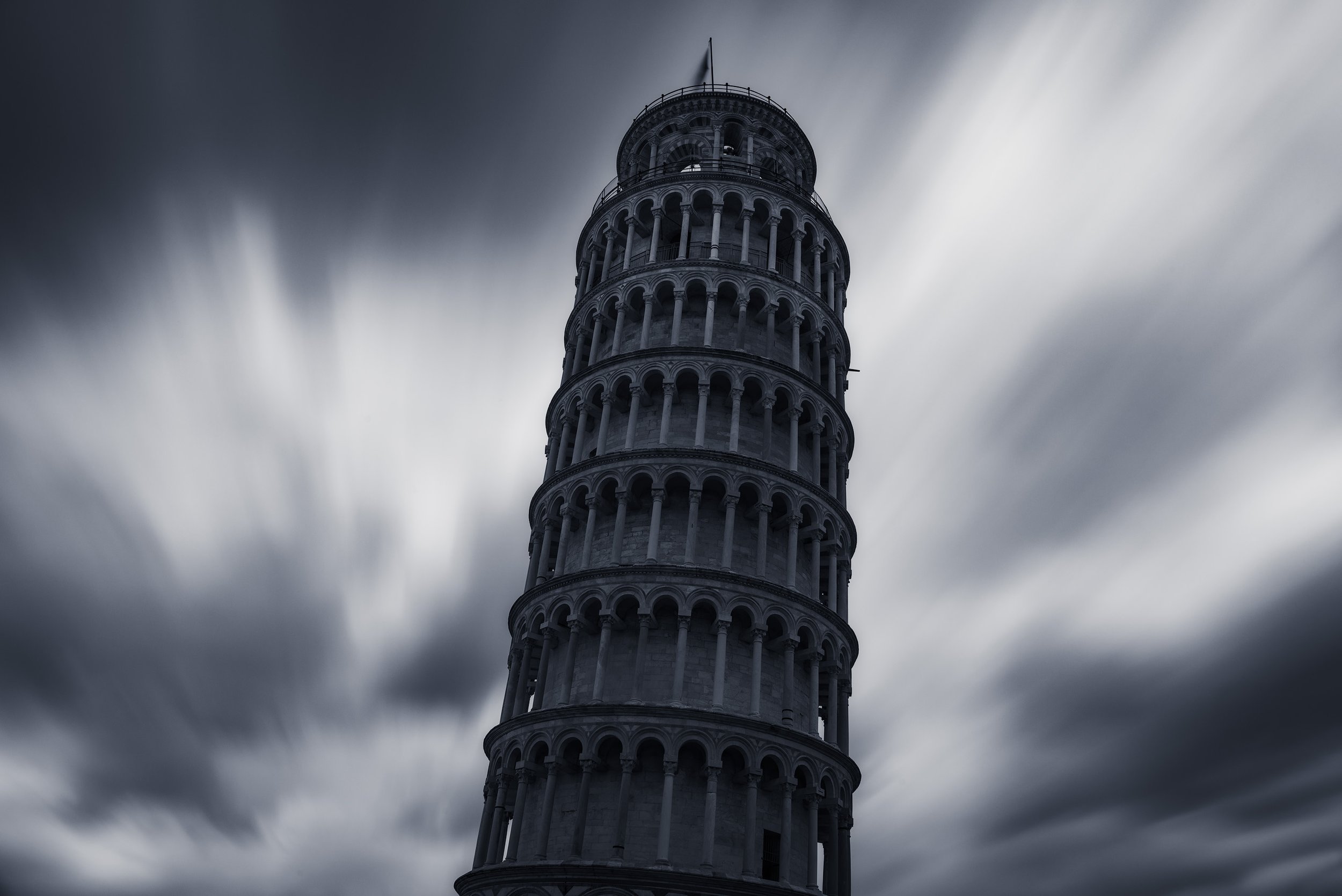 The Leaning Tower of Pisa under a cloudy, overcast sky.