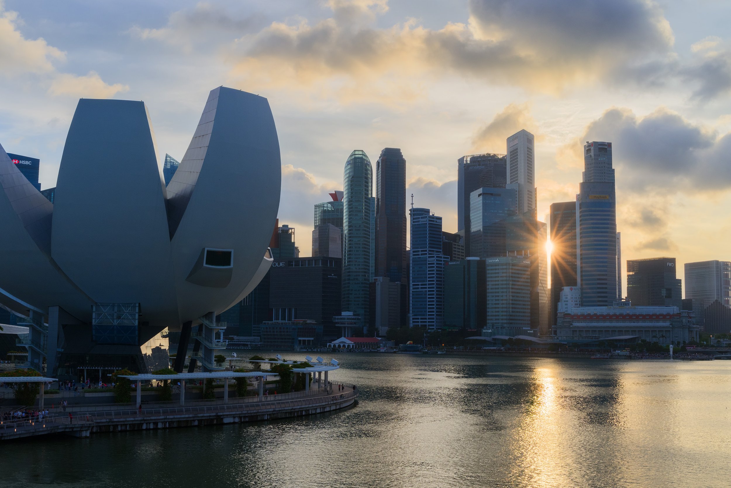 Singapore skyline at sunset with modern skyscrapers and a waterfront view.