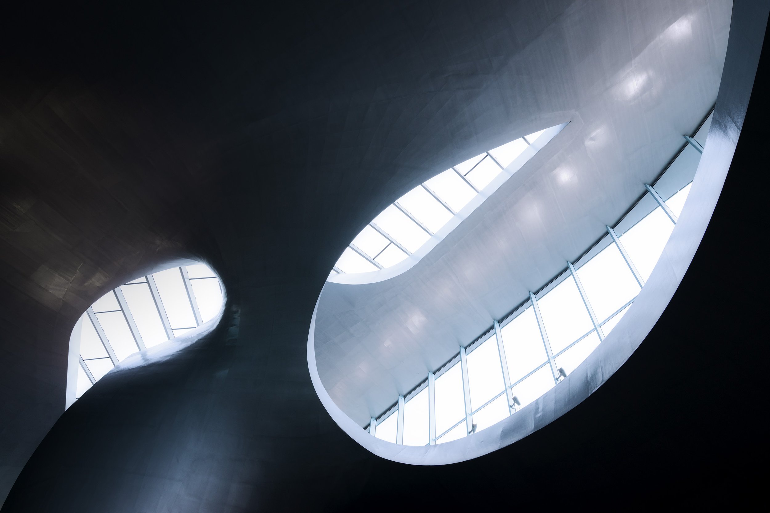 Interior view of a modern building with a curved ceiling and large oval-shaped skylight windows.