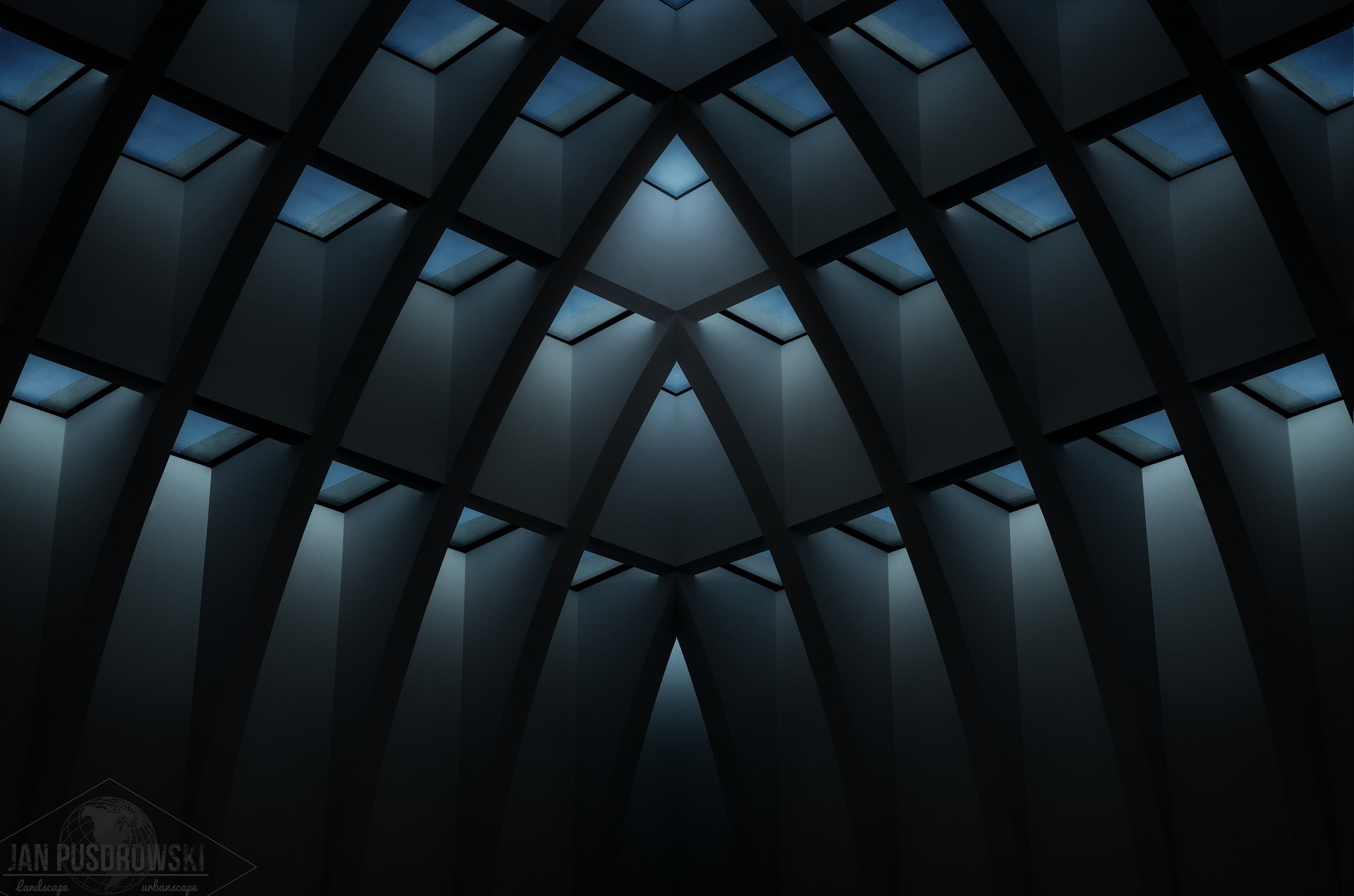 Interior view of a modern architectural roof structure with geometric patterns and skylights.