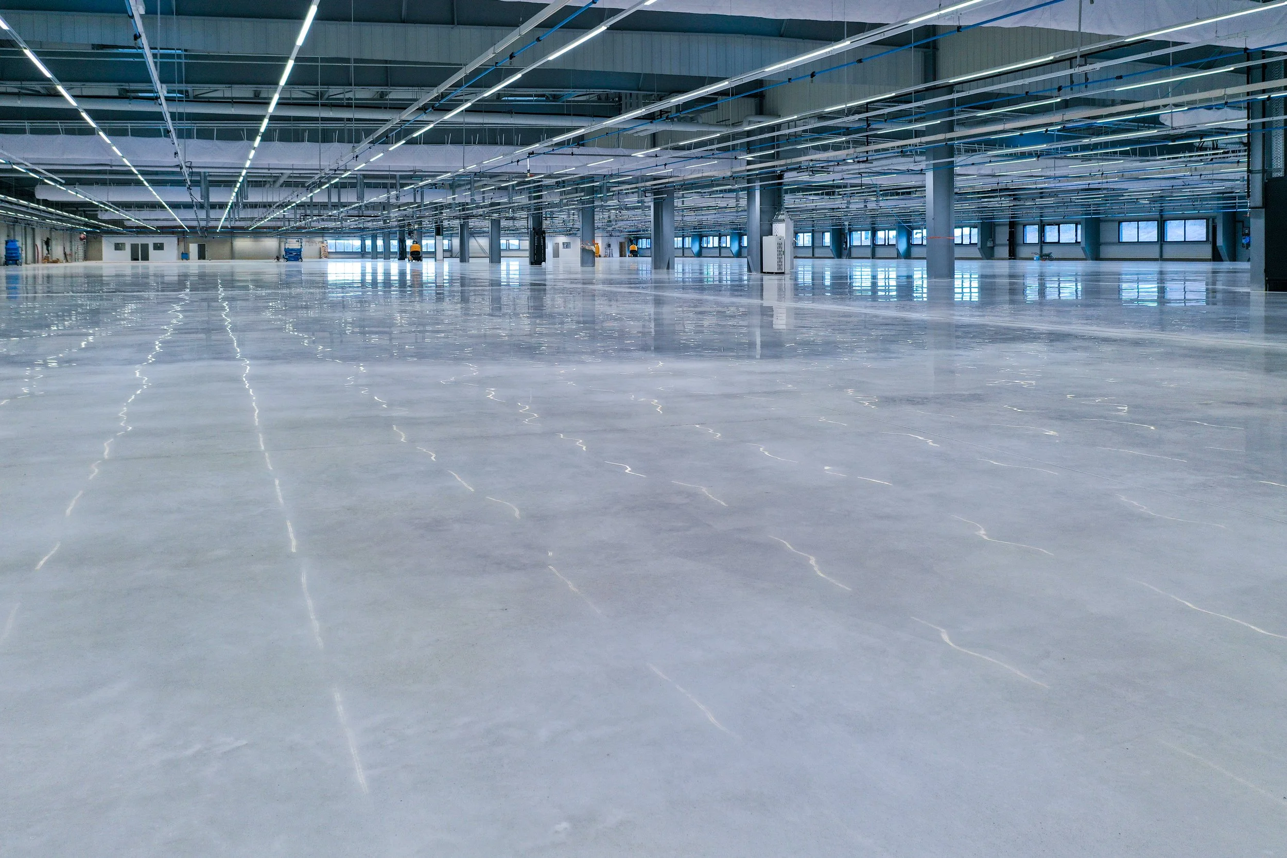 Empty indoor warehouse or factory with bright lighting and shiny polished floor treated with the RINOL DRT system.