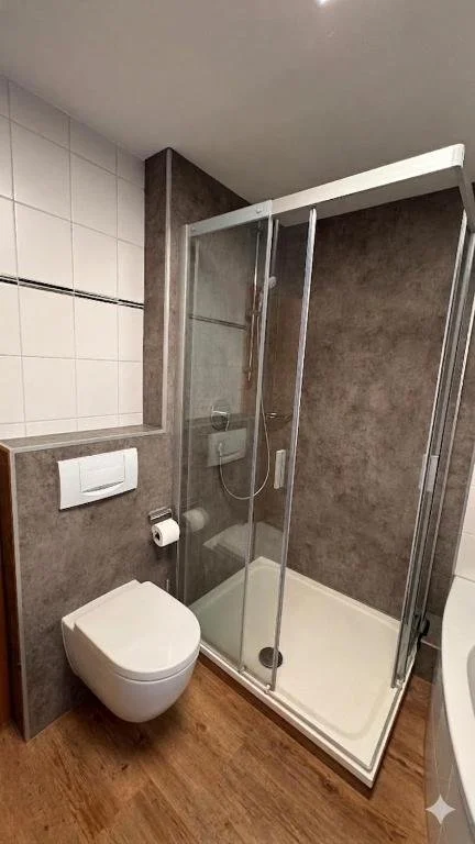 Berg Fux Ferienhaus Grüntenblick Ein Badezimmer mit Dusche, WC und braun-weißen Fliesen.