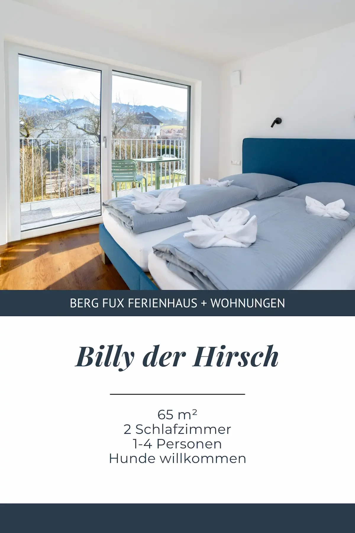 Sehr helles Zimmer mit einem großen Bett,  grauen Bettwäsche und handgefalteten Handtüchern auf dem Bett. Blick auf Berge Text auf dem Bild beschreibt die Unterkunft "Billy der Hirsch" Berg Fux Ferienhaus + Wohnungen