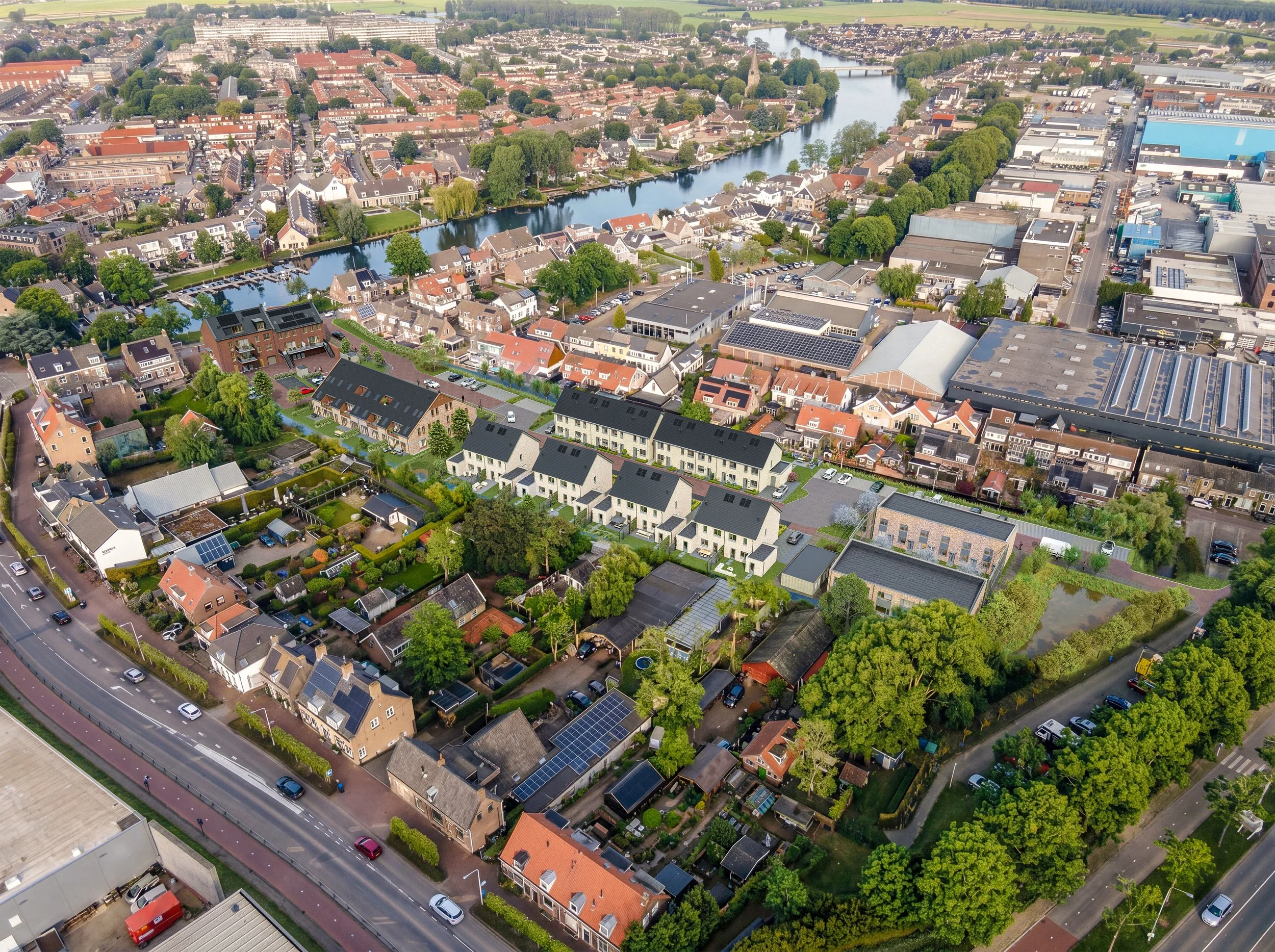 Luchtfoto van een stad met een rivier die door het centrum stroomt, omringd door huizen, gebouwen en groene bomen.