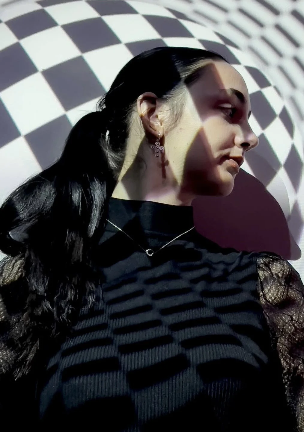 Chica apoyada en una pared fotografiada con una cámara que usa un filtro de rombos