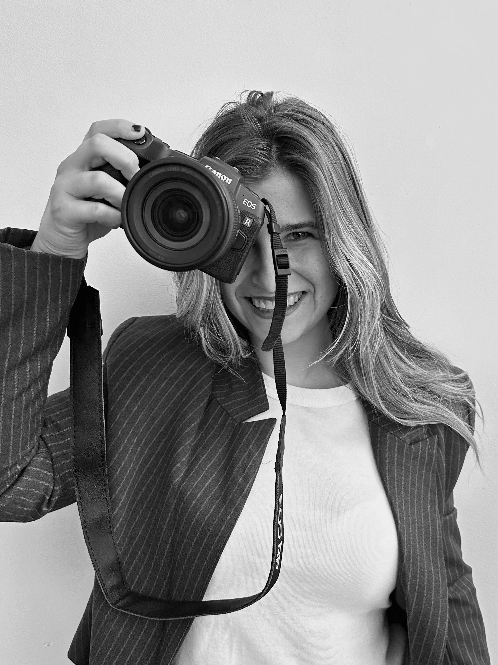 Fotógrafa sosteniendo una cámara sonriendo y creando fotografia lifestyle