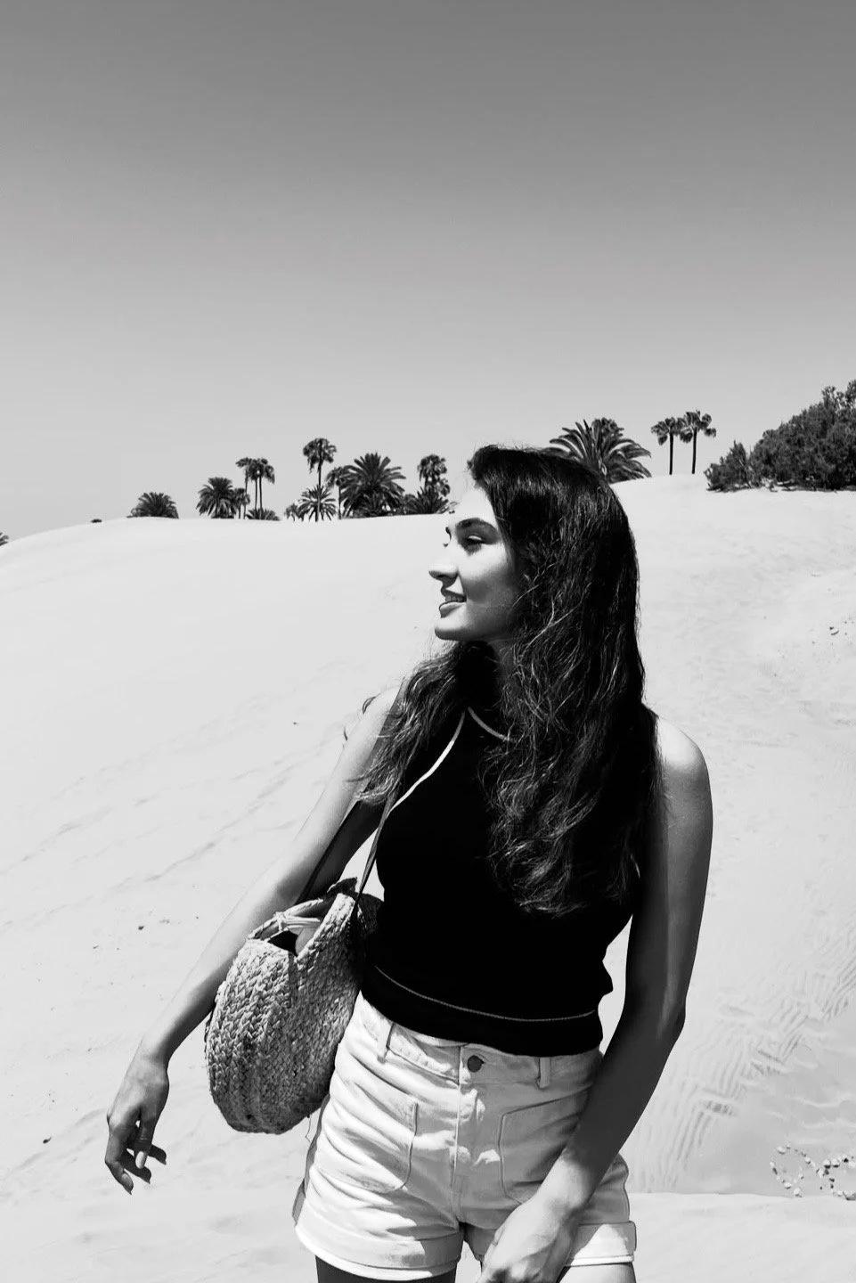 Modelo posando en una playa con un bolso en blanco y negro