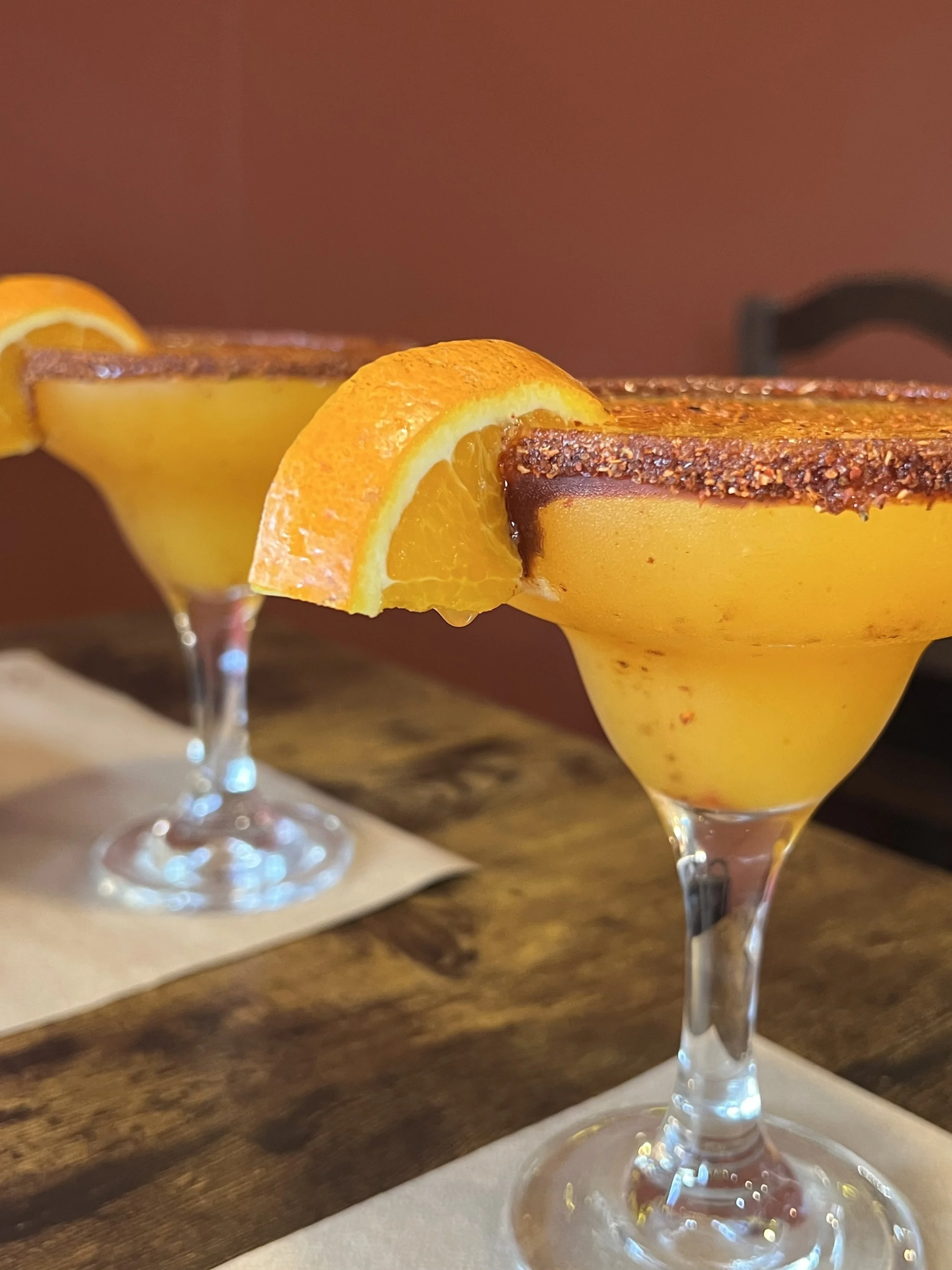 Dos copas de margaritas mexicanos de color naranja sobre una mesa