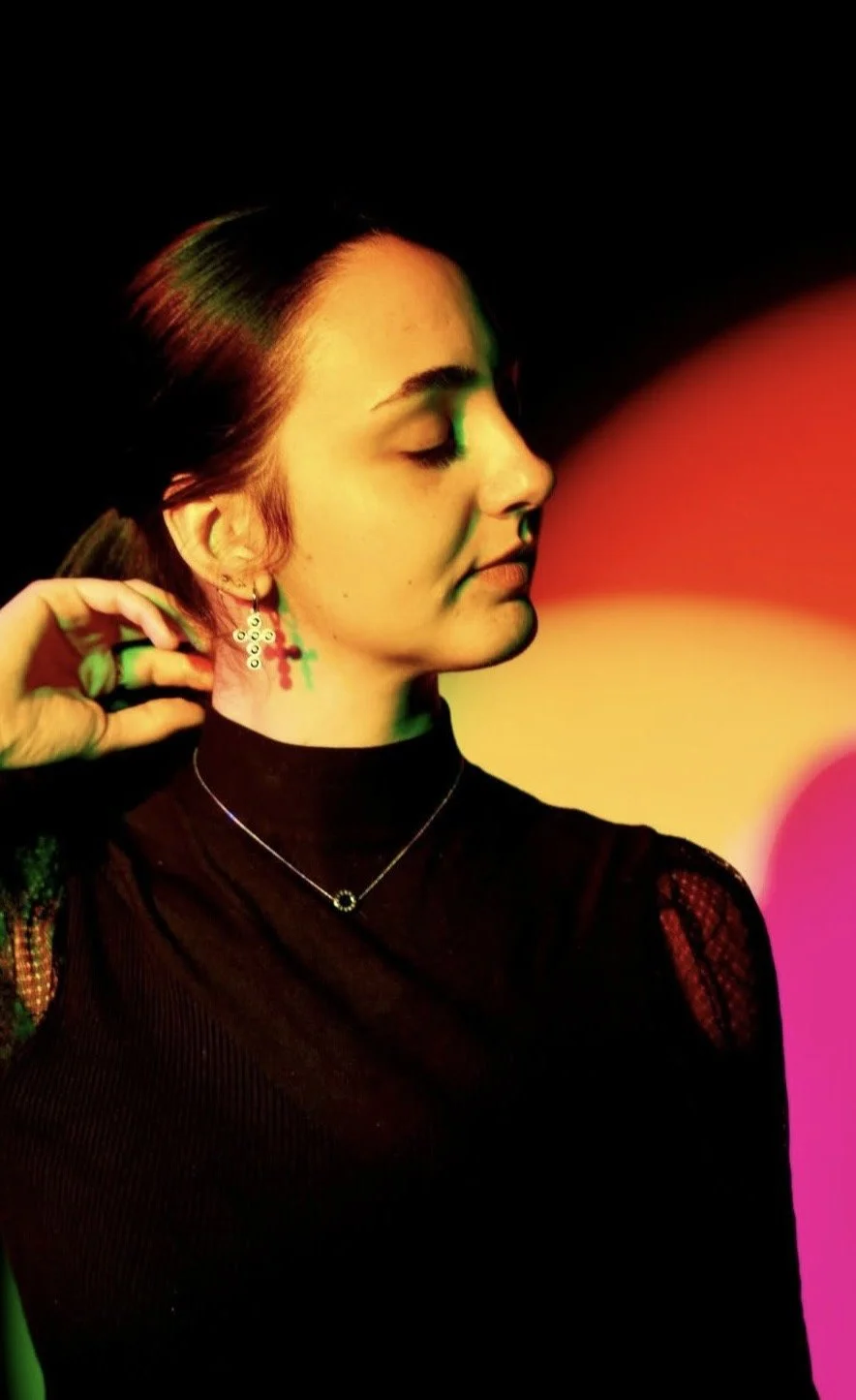 Modelo mostrando joyas en una habitación posando a una cámara con filtros de colores