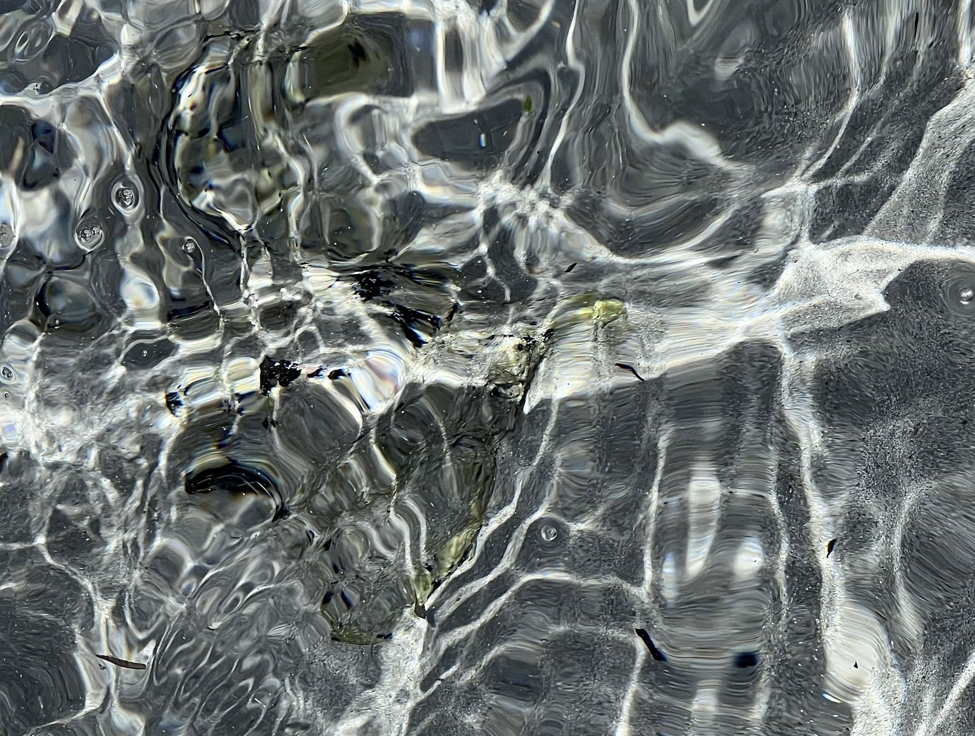 Foto de la textura del agua del mar capturada desde cerca con la arena en el fondo