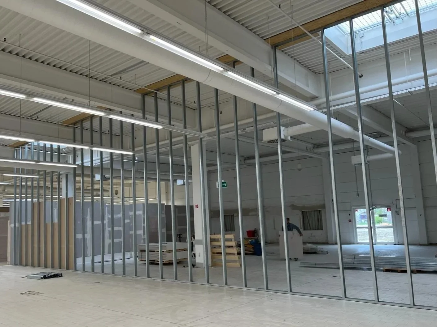 Innenraum eines Gebäudes im Bau, Metallrahmen für Wände und Decken installiert, Baustoffe und Werkzeuge liegen auf dem Boden