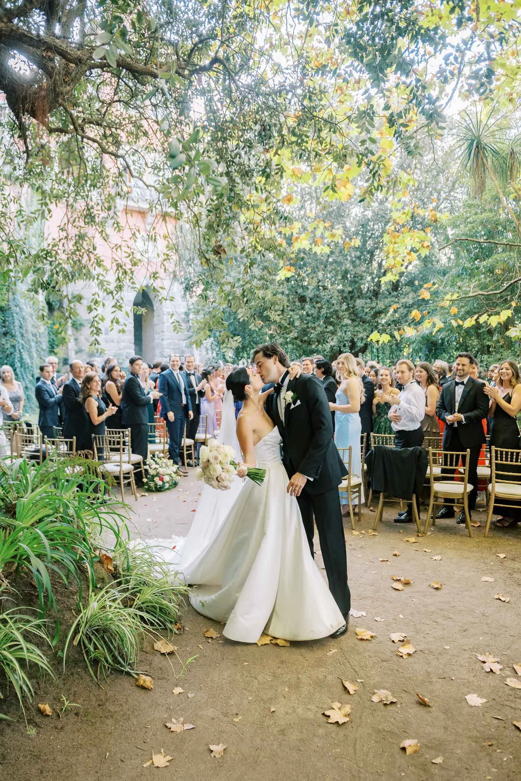 Bride and groom kissing after the ceremony with guests in the background at Casa dos Penedos in Sintra