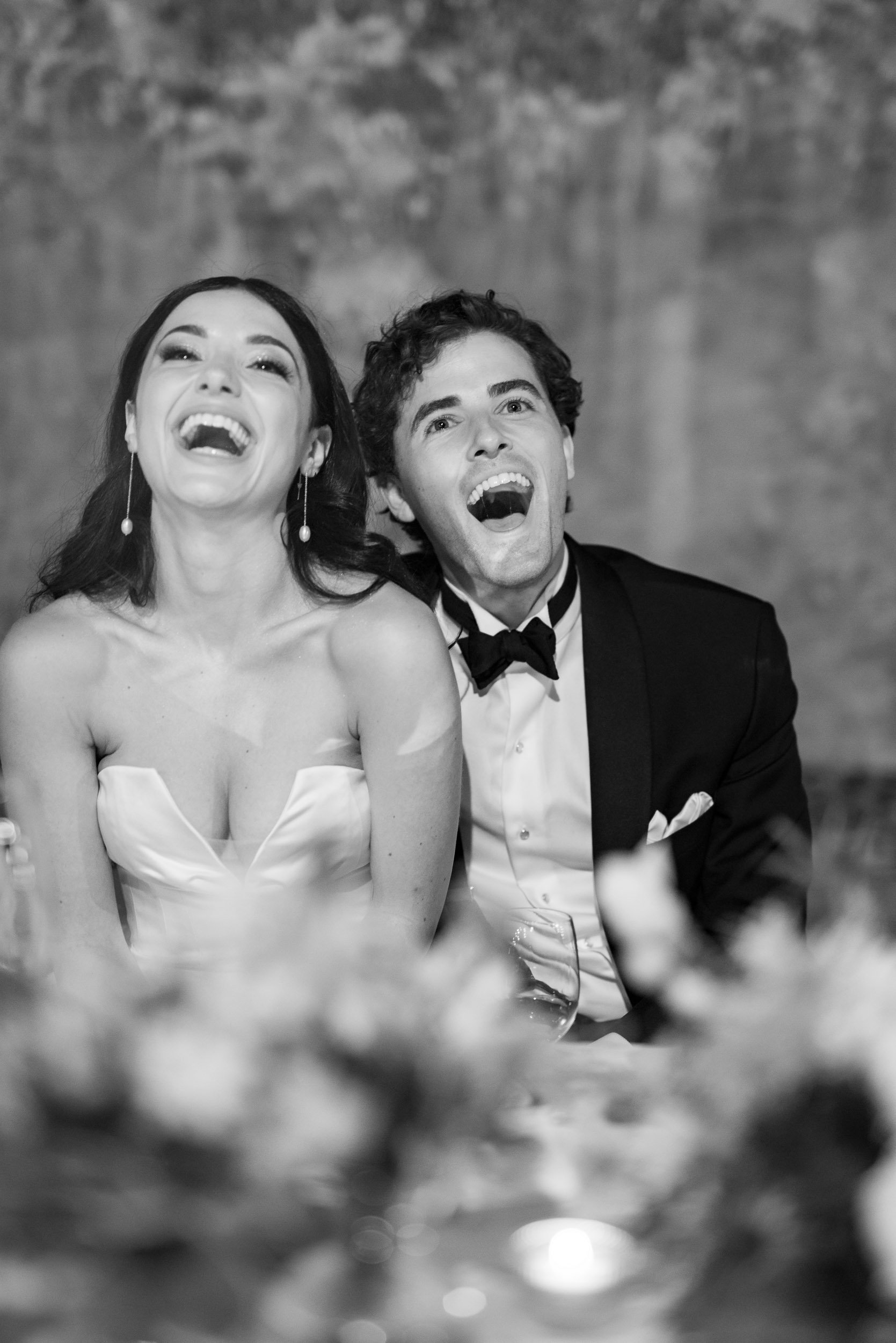Bride and groom laughing during dinner at an elegant wedding reception