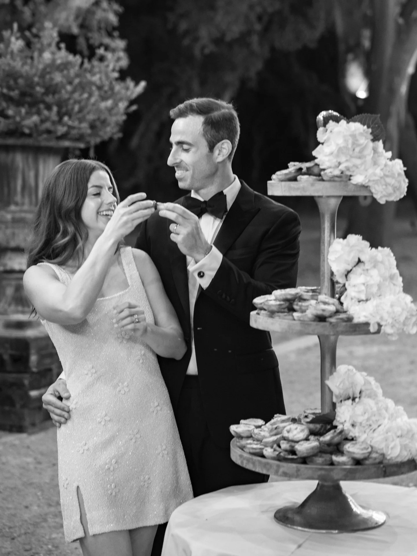 Couple sharing pastries together during an outdoor wedding reception